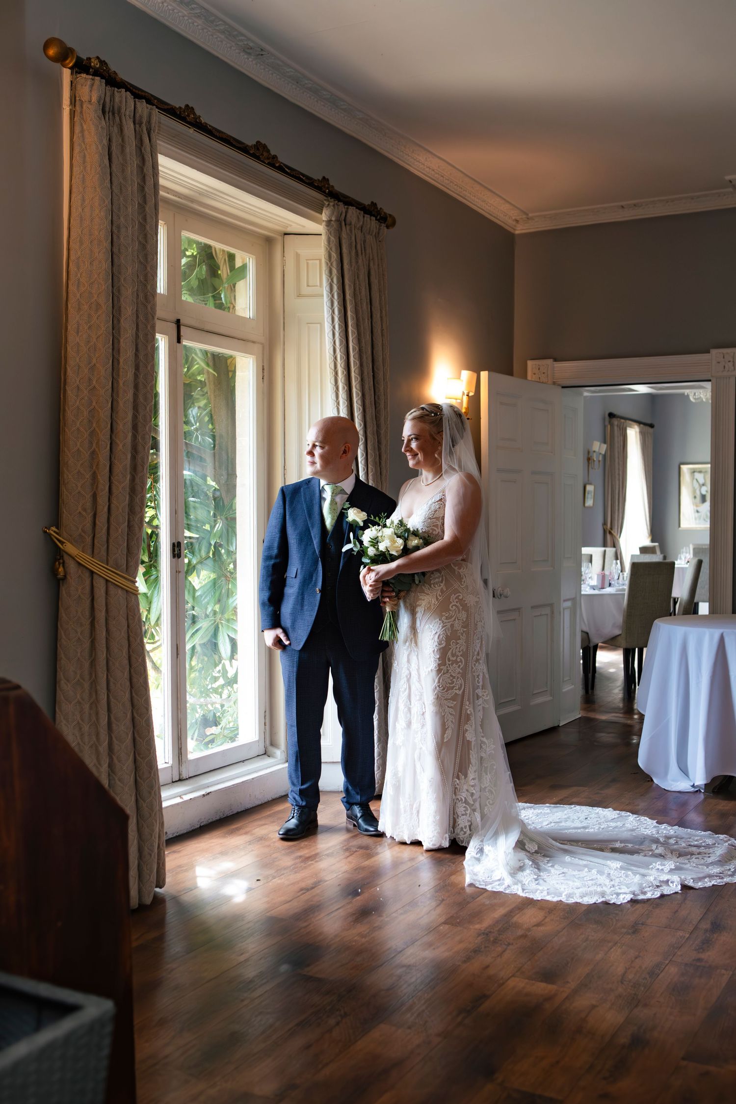 Wedding couple photographed in a sunlit room with hardwood floors and elegant decor.
