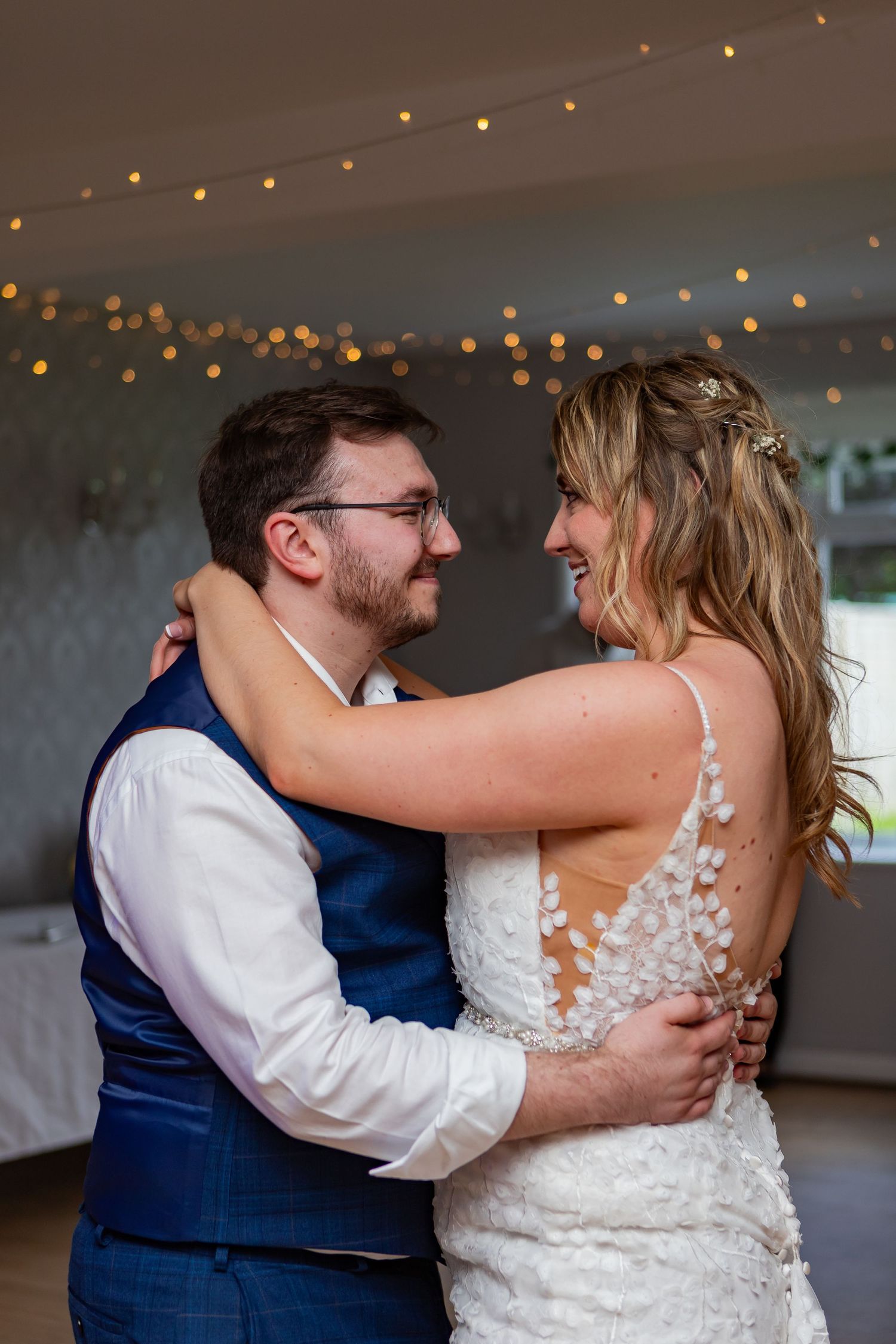 Couple shares an intimate dance moment under twinkling lights at their wedding reception.