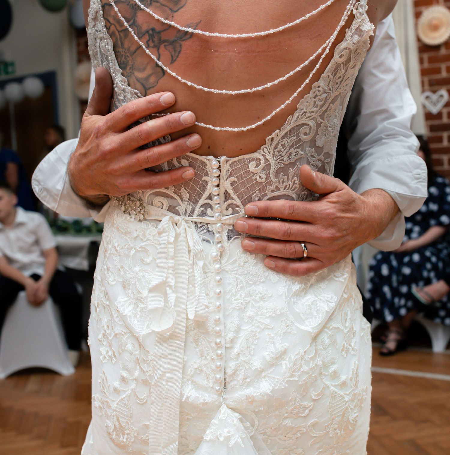 Close-up detail of intricate lace wedding dress back with delicate buttons.