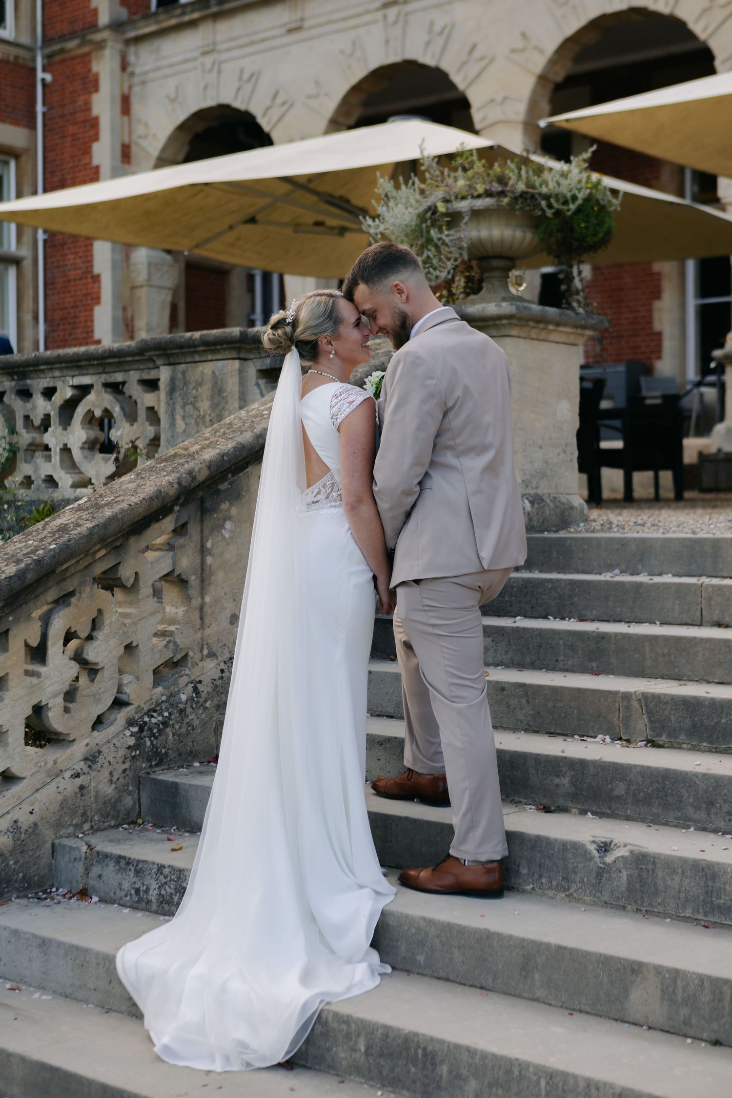 Elegant wedding portrait on grand stone steps with architectural details and parasol.