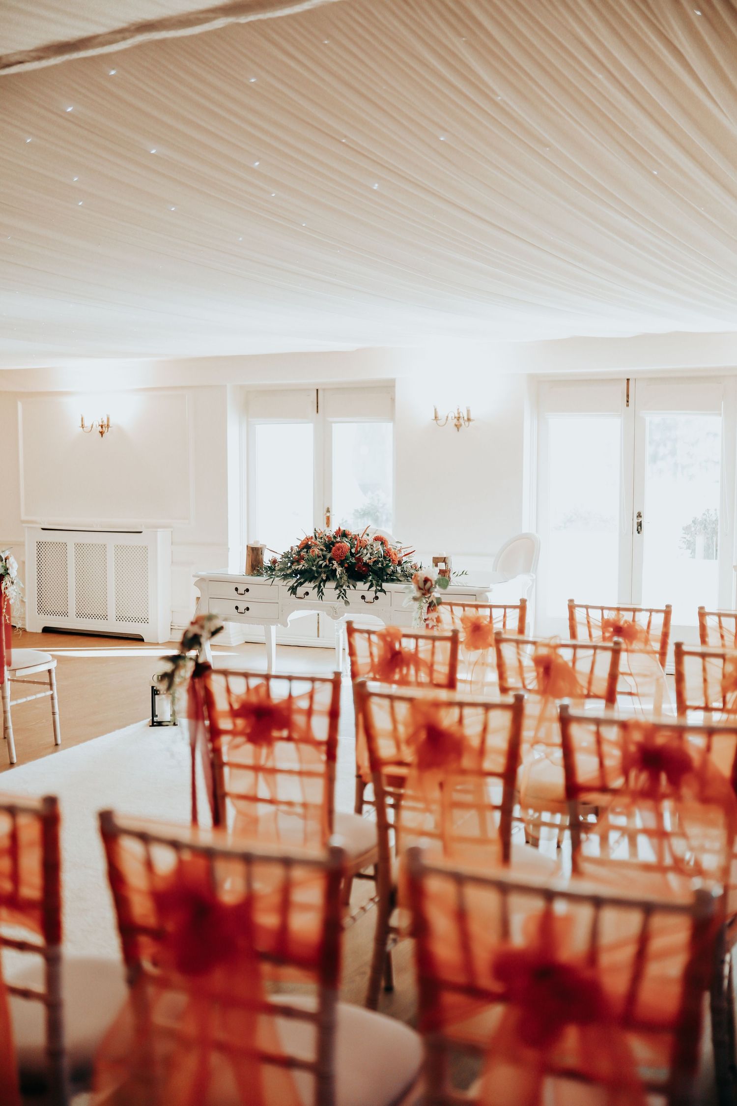 Reception venue with red chairs and white ceiling decor set up for a wedding celebration.