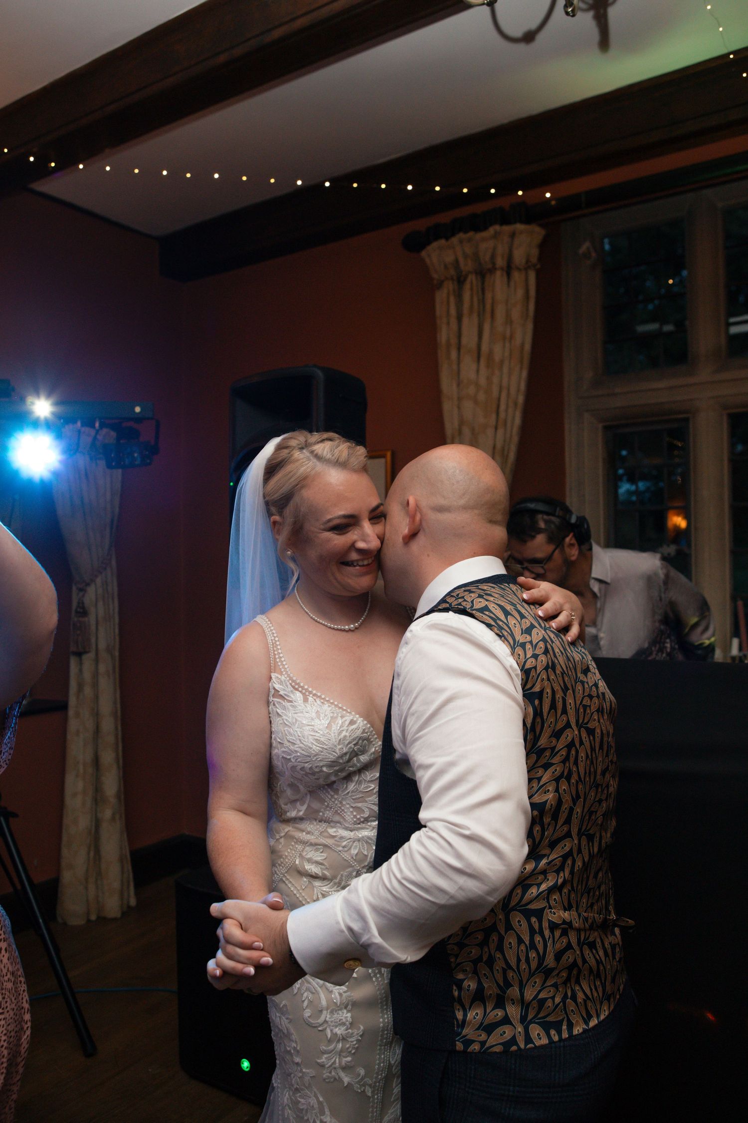 Couples dancing at wedding reception with string lights in background.
