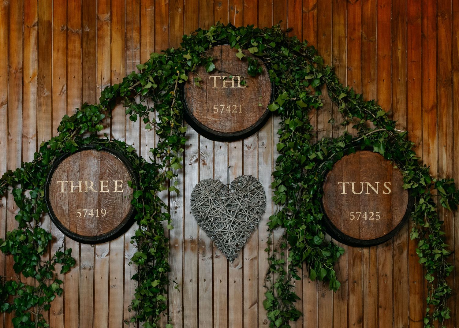 Wooden wall decorated with wine barrels and climbing ivy for wedding decor.