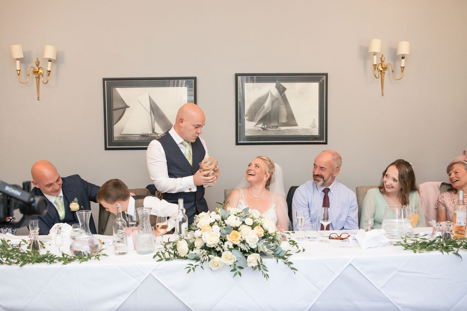 Wedding reception head table with floral arrangements and formal place settings.