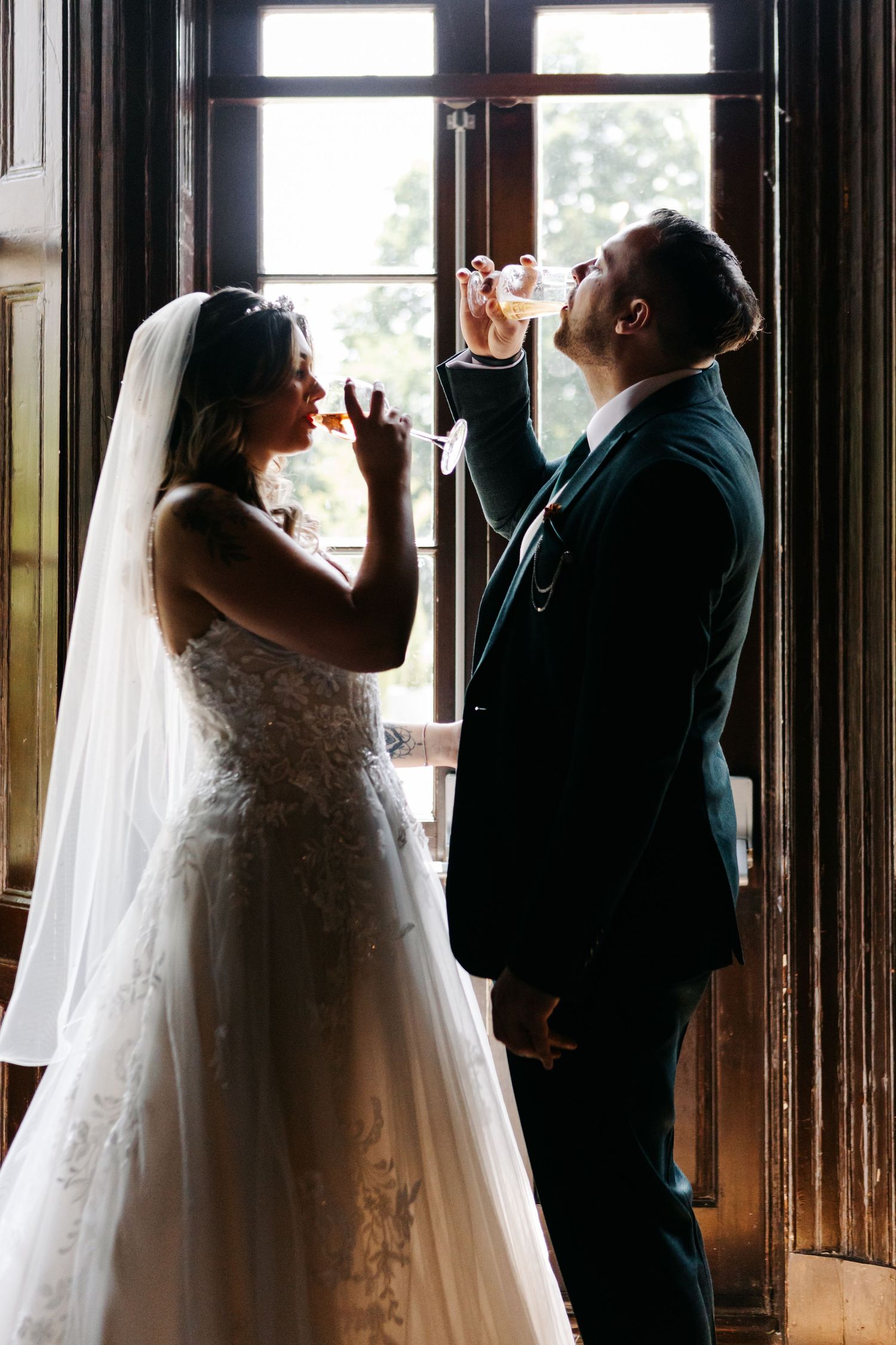 A romantic moment captured in silhouette against bright windows in an elegant venue.