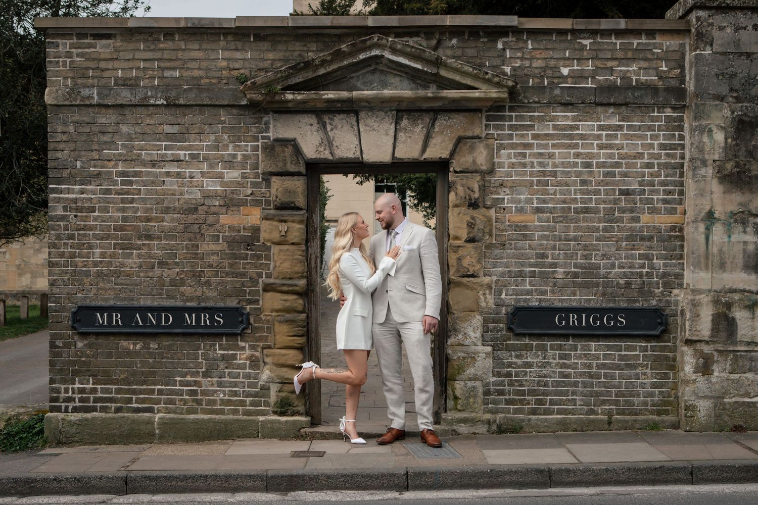 Brick wall with vintage signage serves as backdrop for romantic photoshoot.