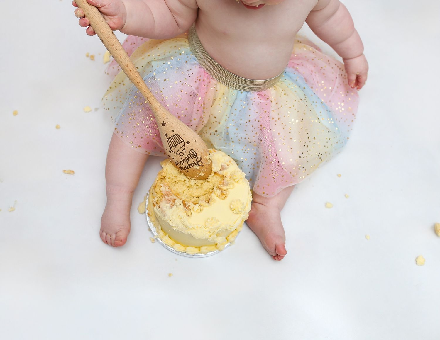 Close-up of baby's hands and feet playing with cake during a smash cake photo session.