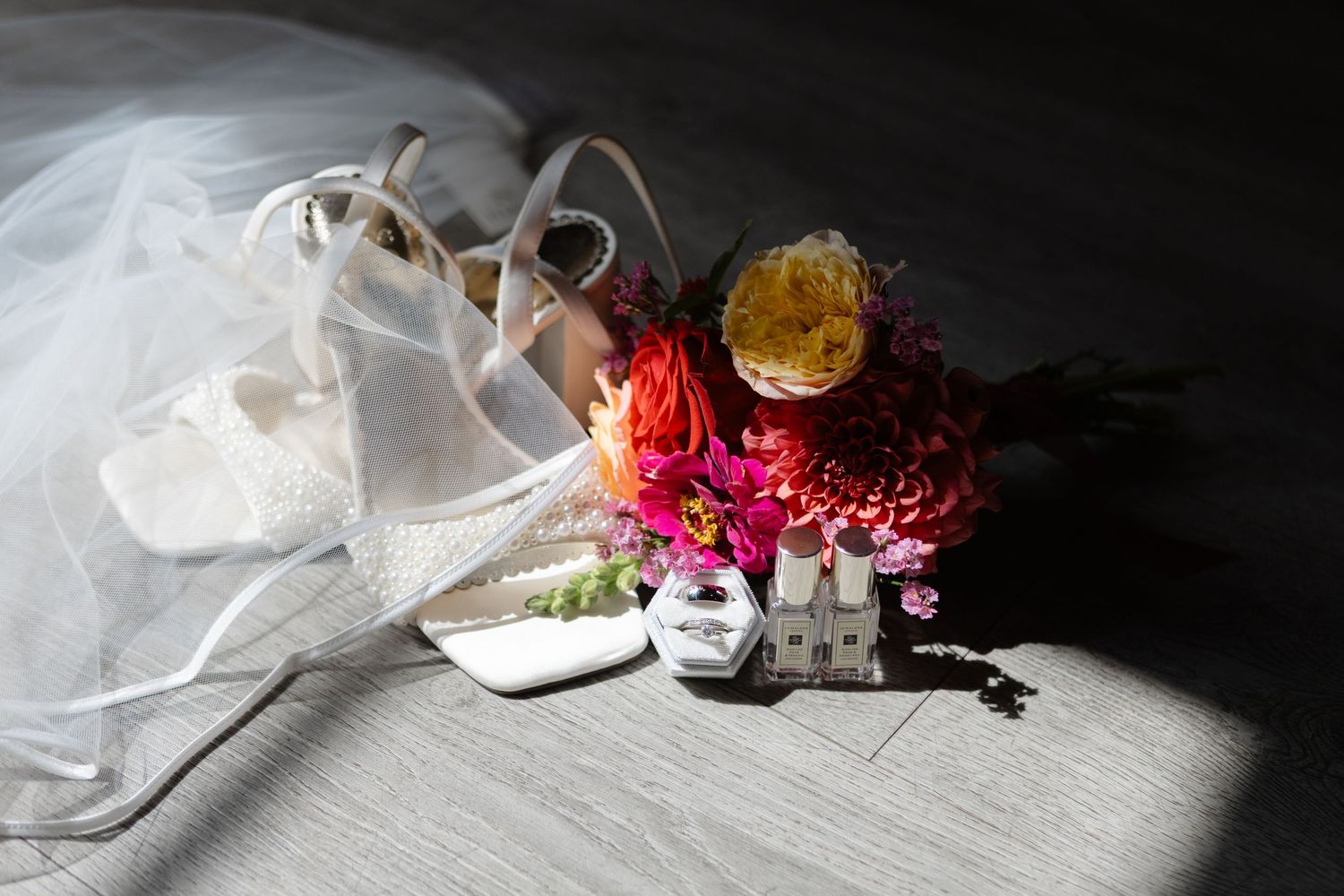 Bridal shoes with delicate floral accents photographed in dramatic lighting.