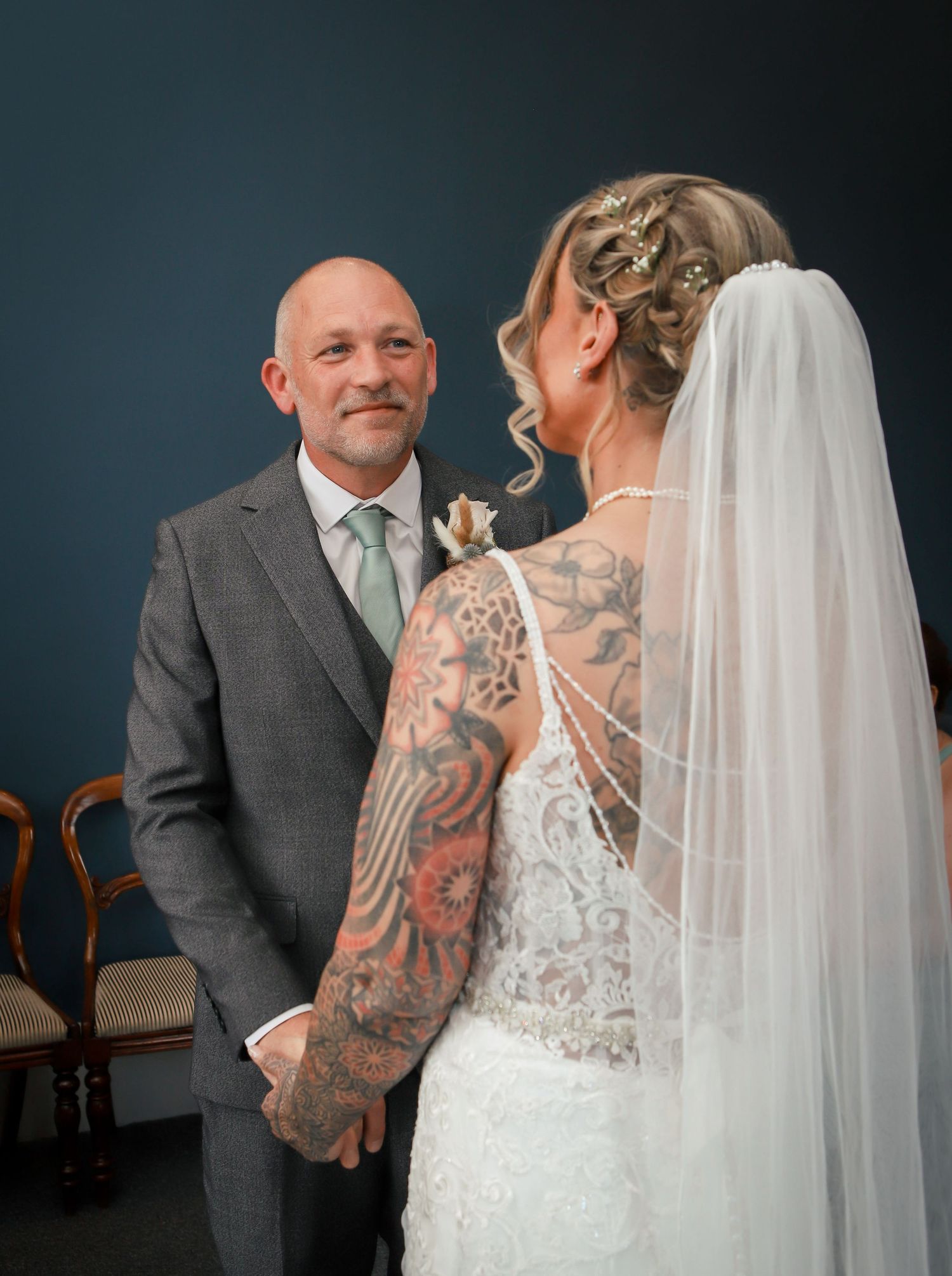 Intimate wedding couple moment with bride in lace dress and visible tattoos.