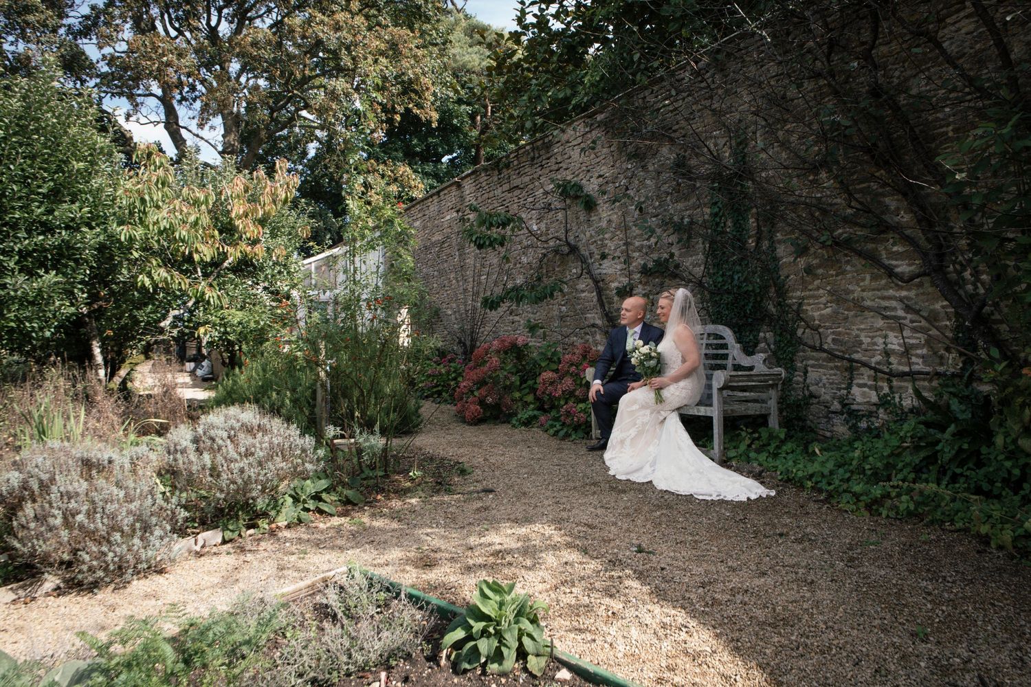 Scenic outdoor wedding venue with natural stone walls and garden landscaping.