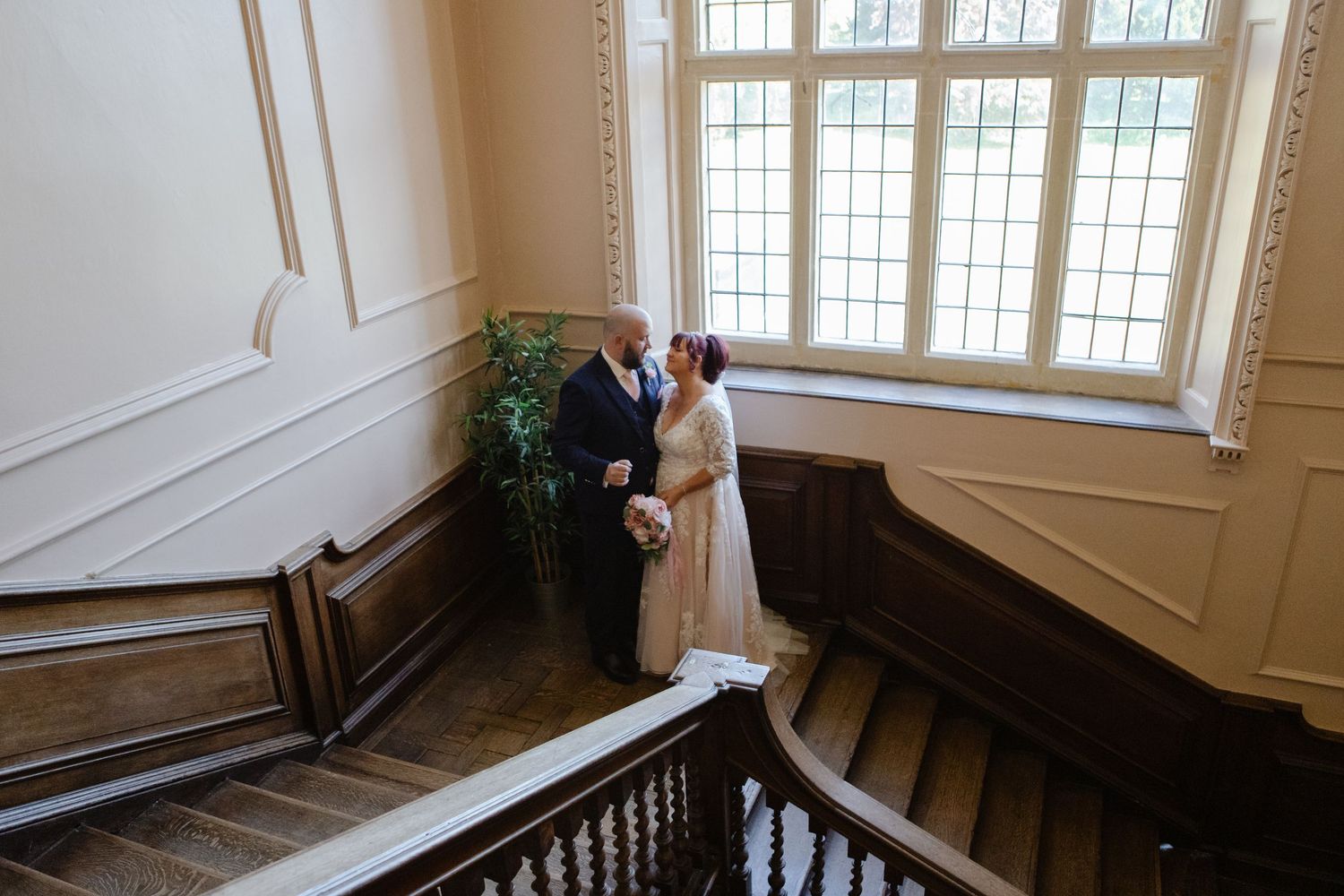 Interior shots of grand staircase with ornate wooden railings and large windows.