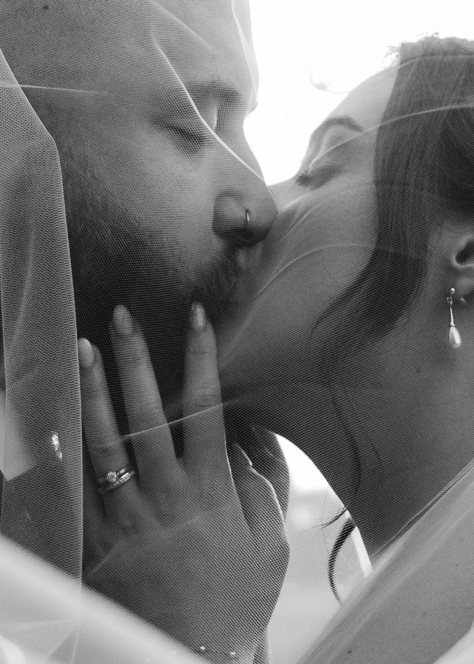 Romantic black and white wedding portrait through delicate veil.
