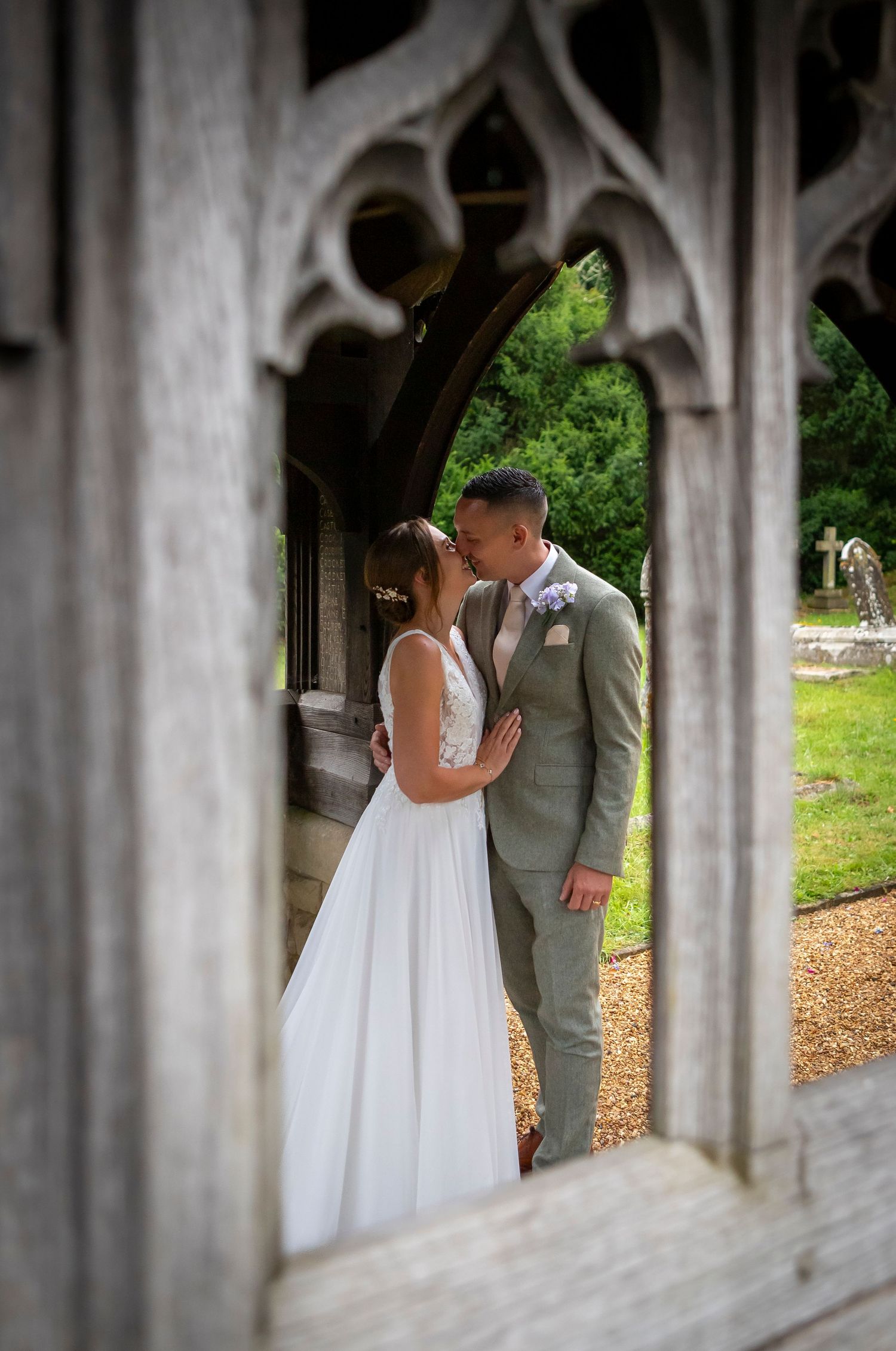 A romantic wedding couple shares intimate moments under stone archways in an outdoor setting.
