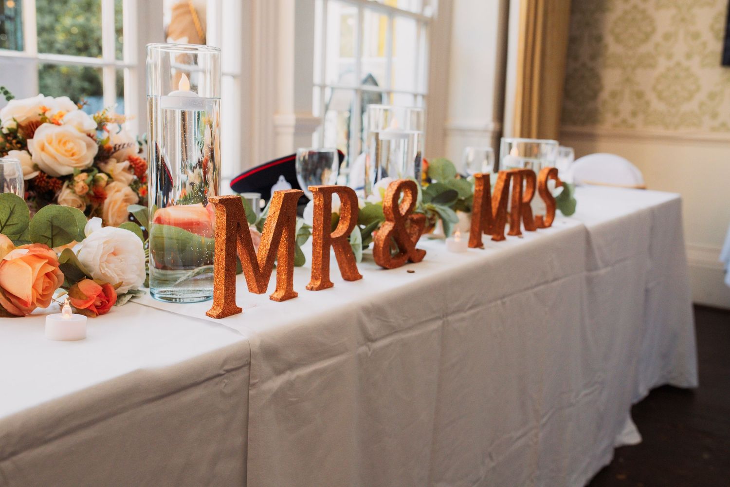 Orange Mr & Mrs letters decorate an elegant wedding reception table with autumn-themed floral arrangements.