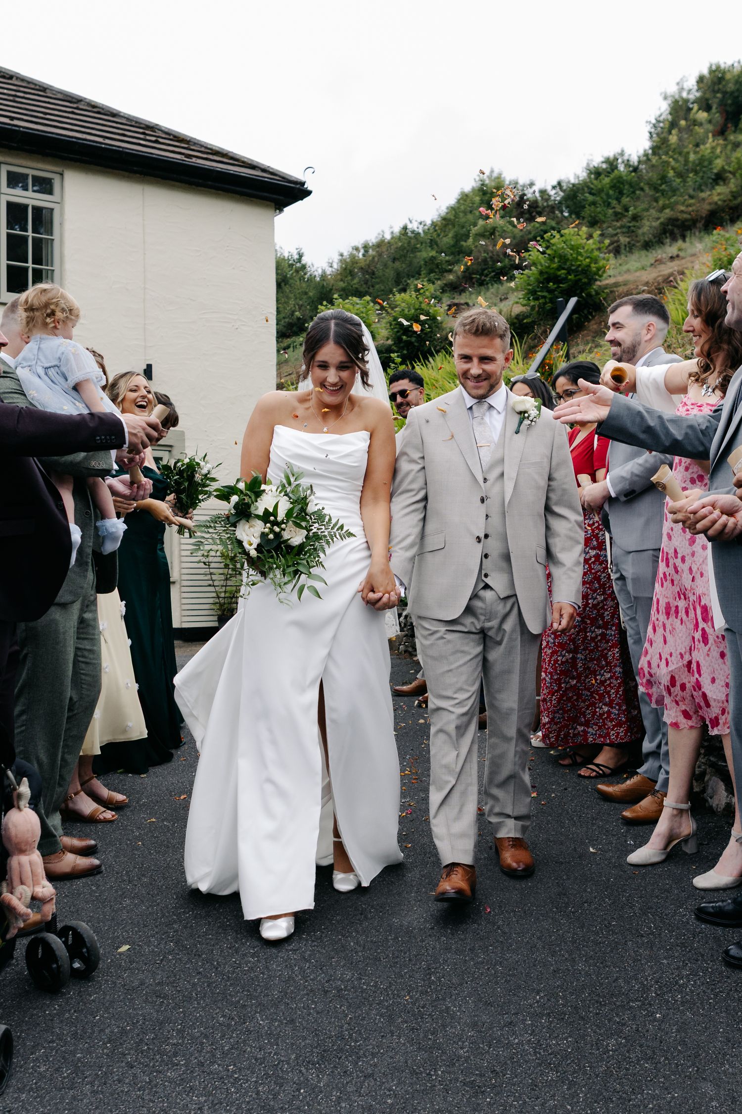 Wedding party lines up on asphalt for celebratory photos.