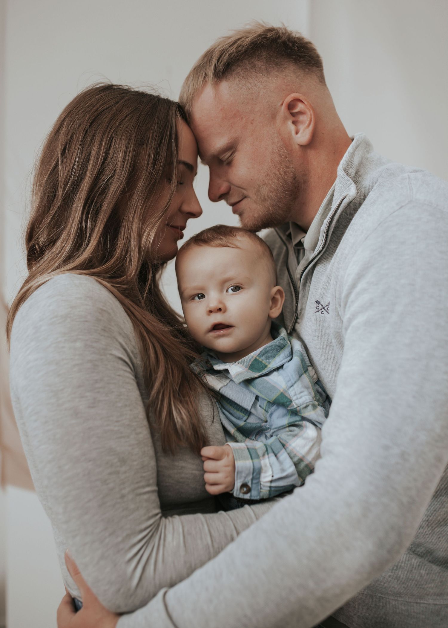 Intimate family portrait session with matching grey sweaters and casual styling.