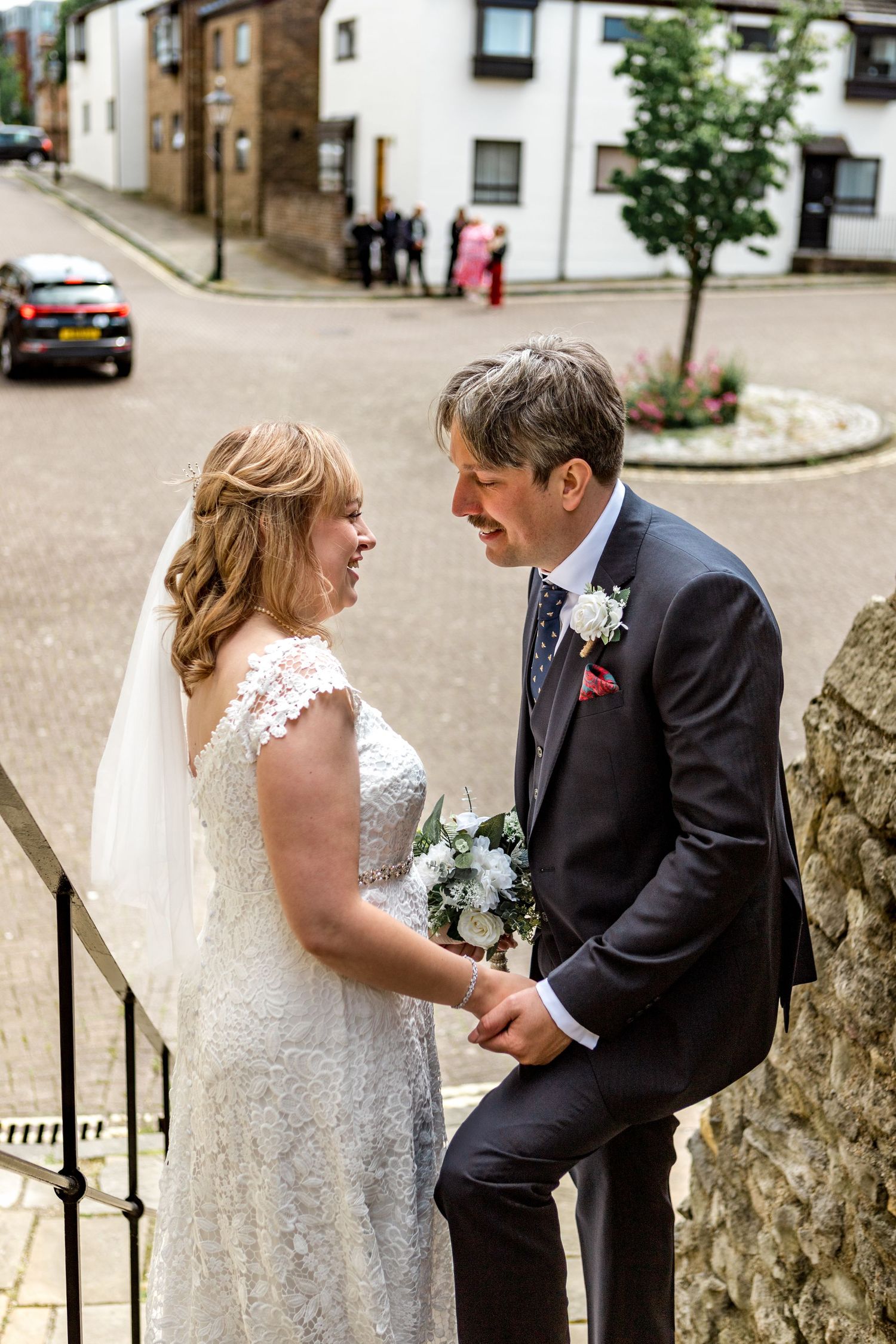 Candid moment of laughter between bride and groom on stone steps.