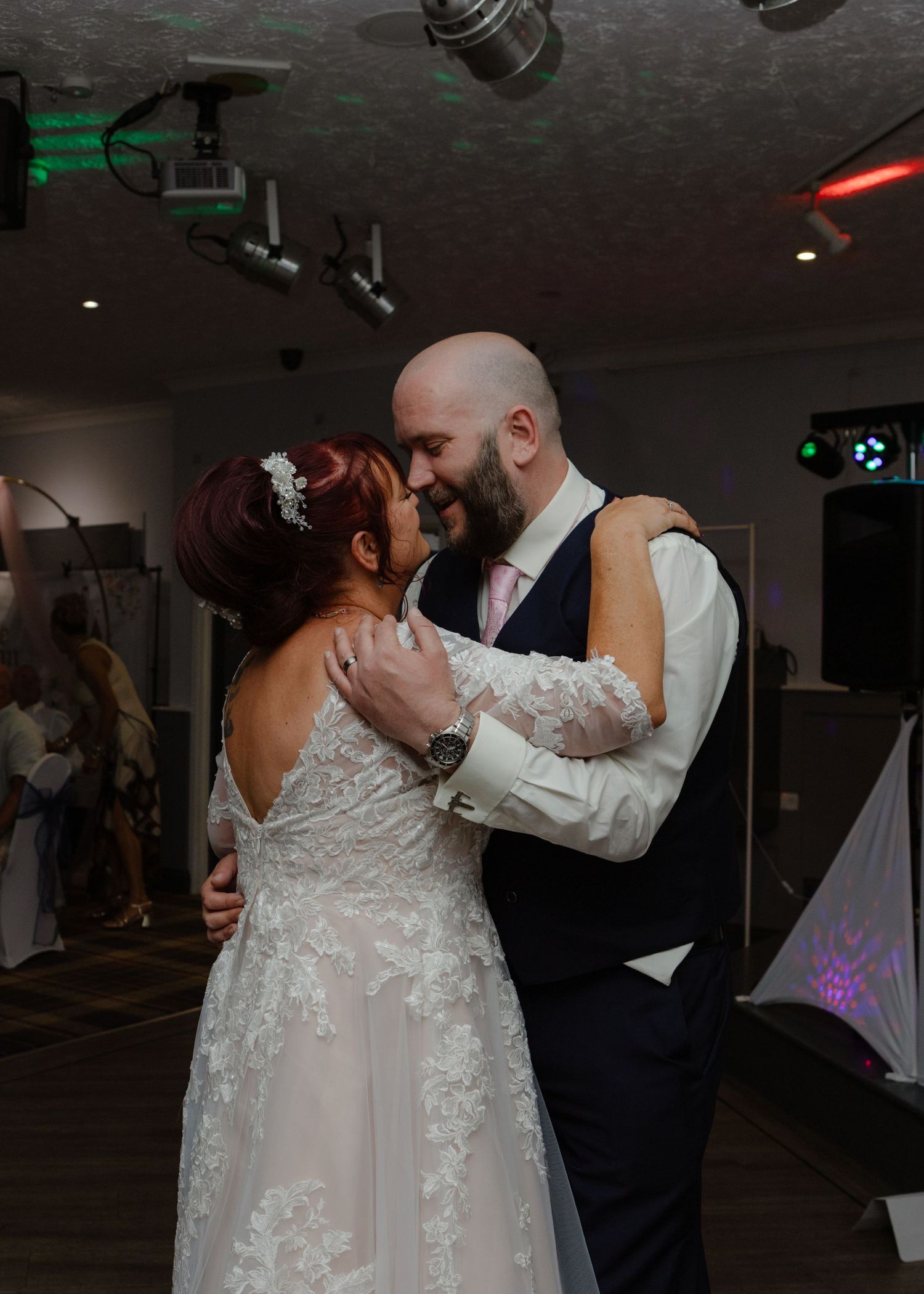 Wedding couple performing romantic dance moves at dimly lit indoor reception.