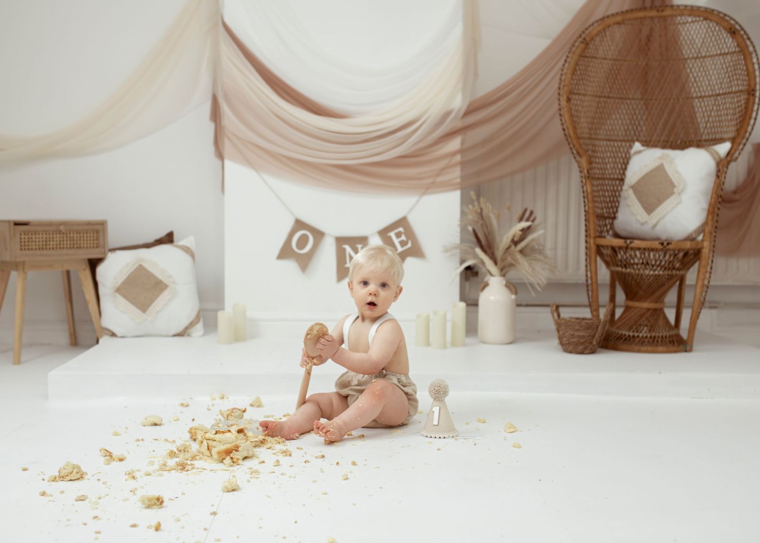 White studio setup with rustic decor and banner for baby's first birthday cake smash session.