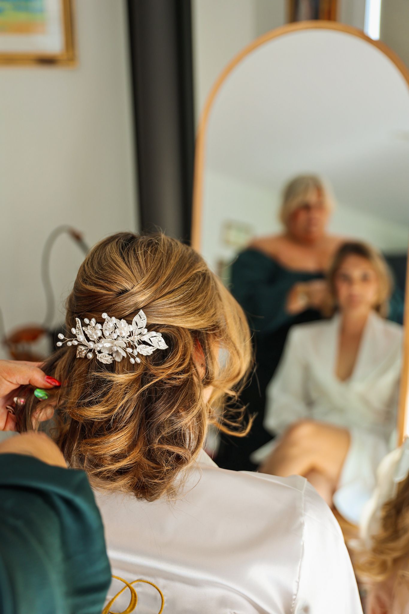 Bride having finishing touches and curls placed in her hair before her wedding.