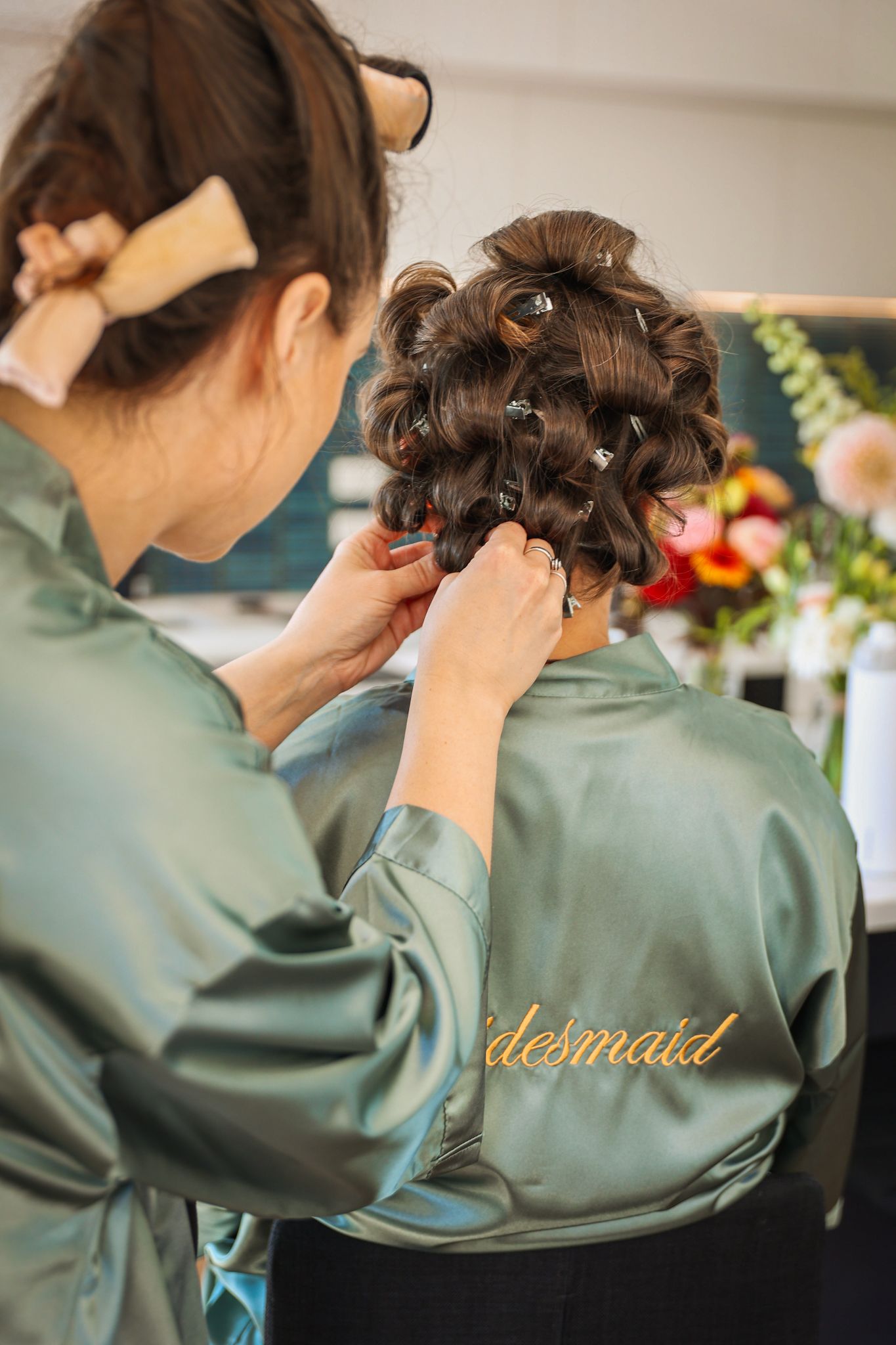 Bridesmaids helping each other unroll curlers.