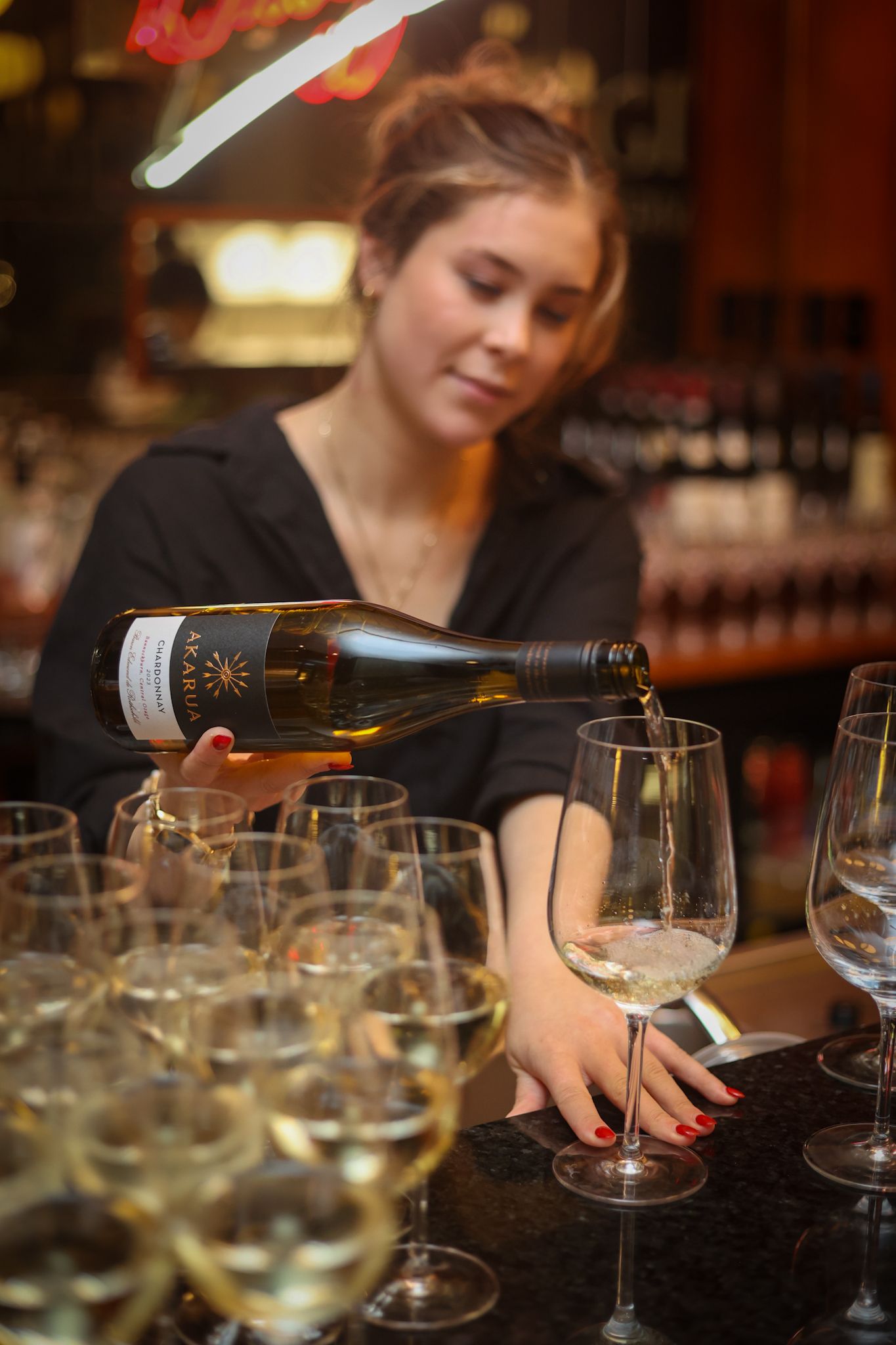 A lady pouring a glass of wine at a wine event.
