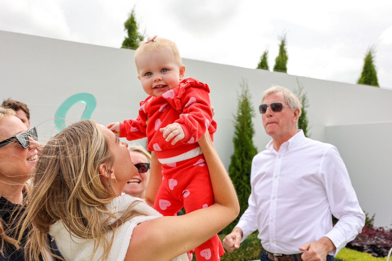 A family party after a wedding, bride holding up her niece in the air.