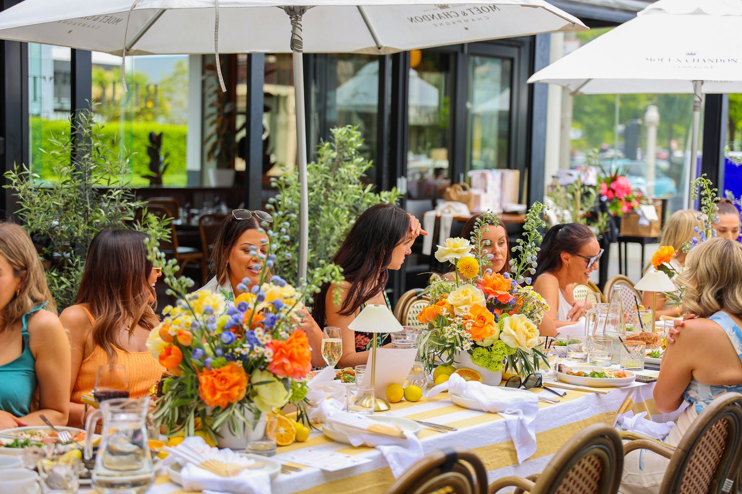 A birthday summer garden party in the courtyard at Brigitte’s Merivale. A dining table with bright flowers.