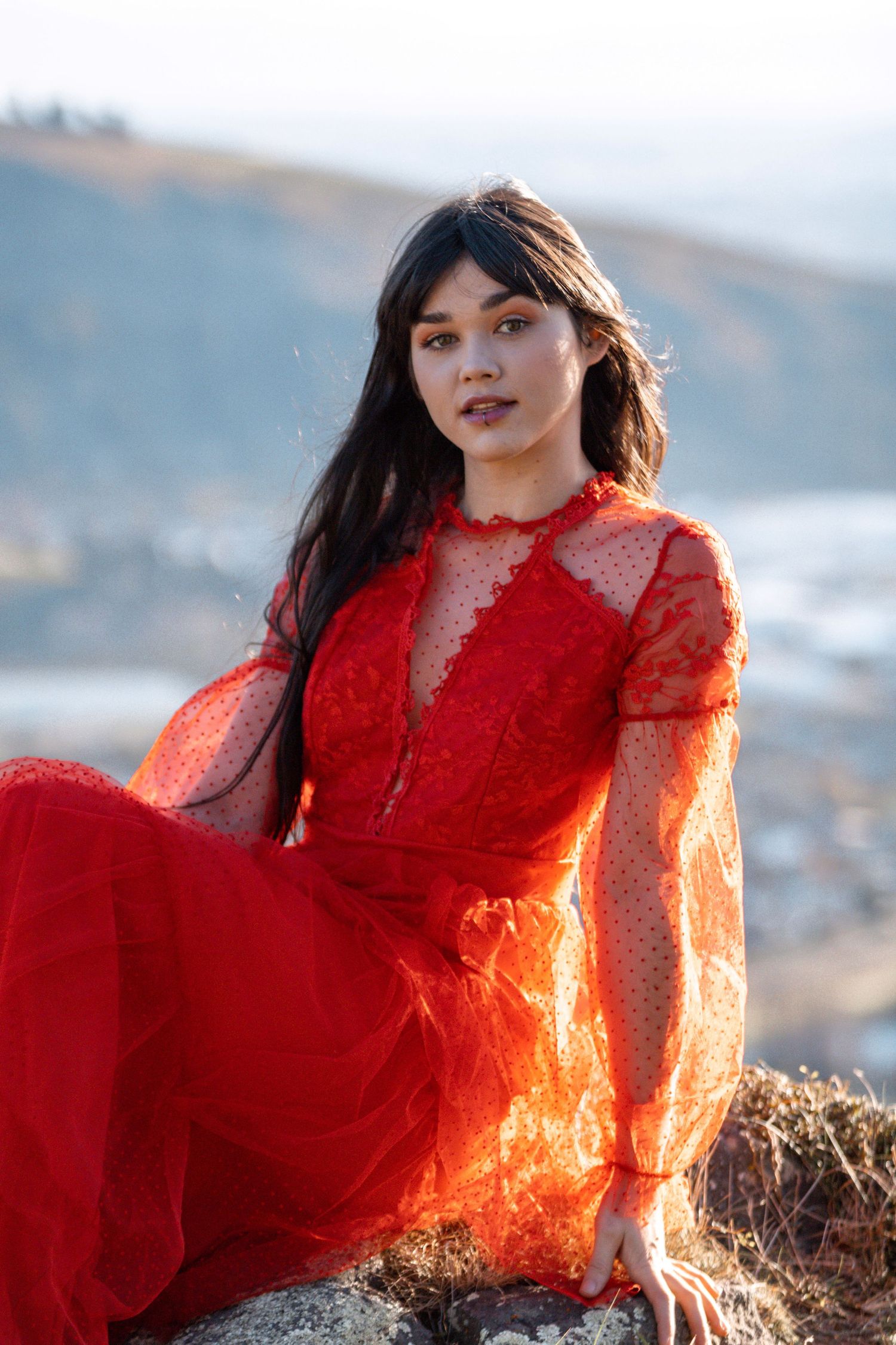 Model in a red dress posing against the Christchurch Port Hills during a portfolio photoshoot