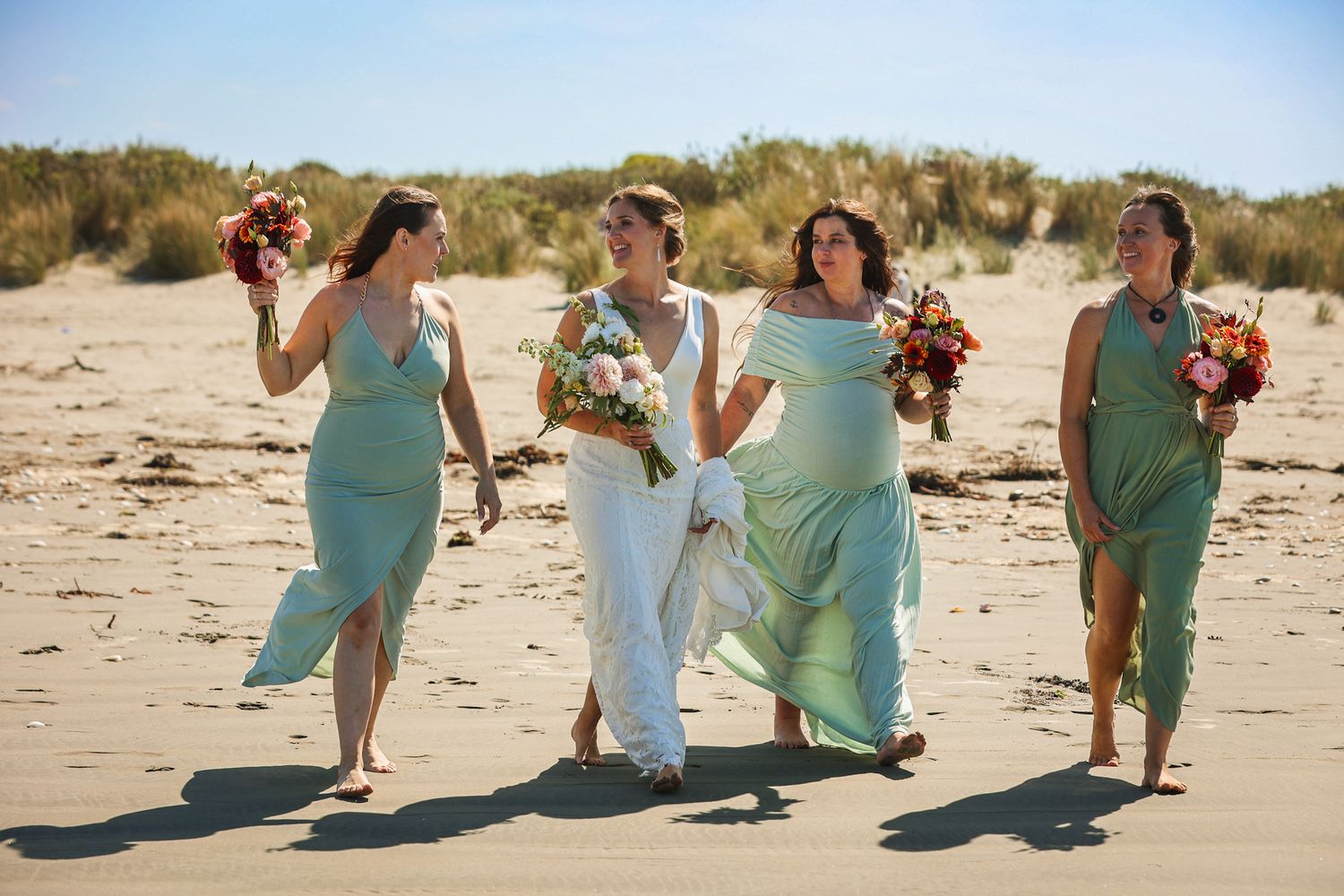 Bride and bridesmaids walking barefoot in the sand for some candid portrait shots