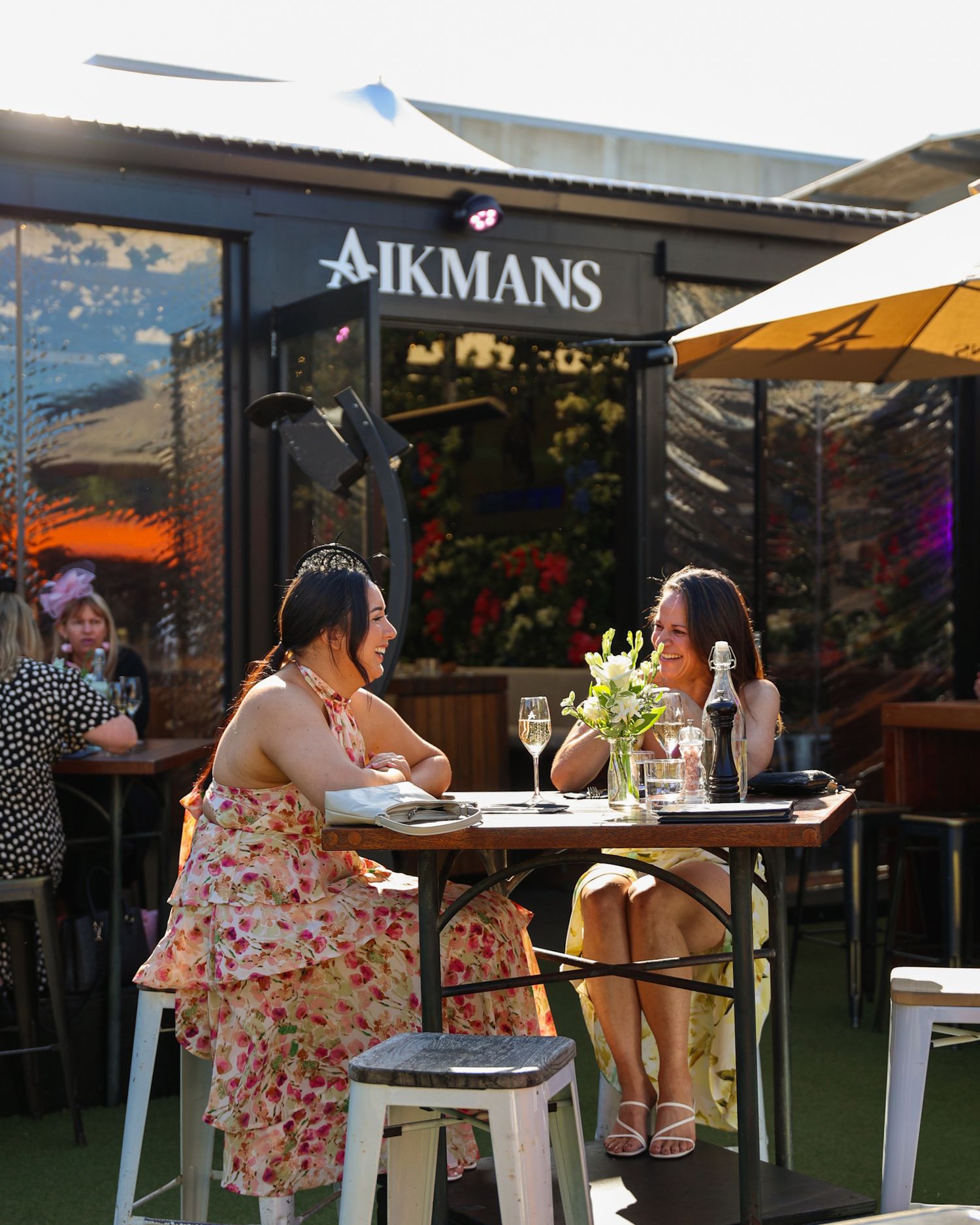 Two ladies in race-day-attire sitting at Aikmans Merivale during Cup Week at Aikmans Merivale.