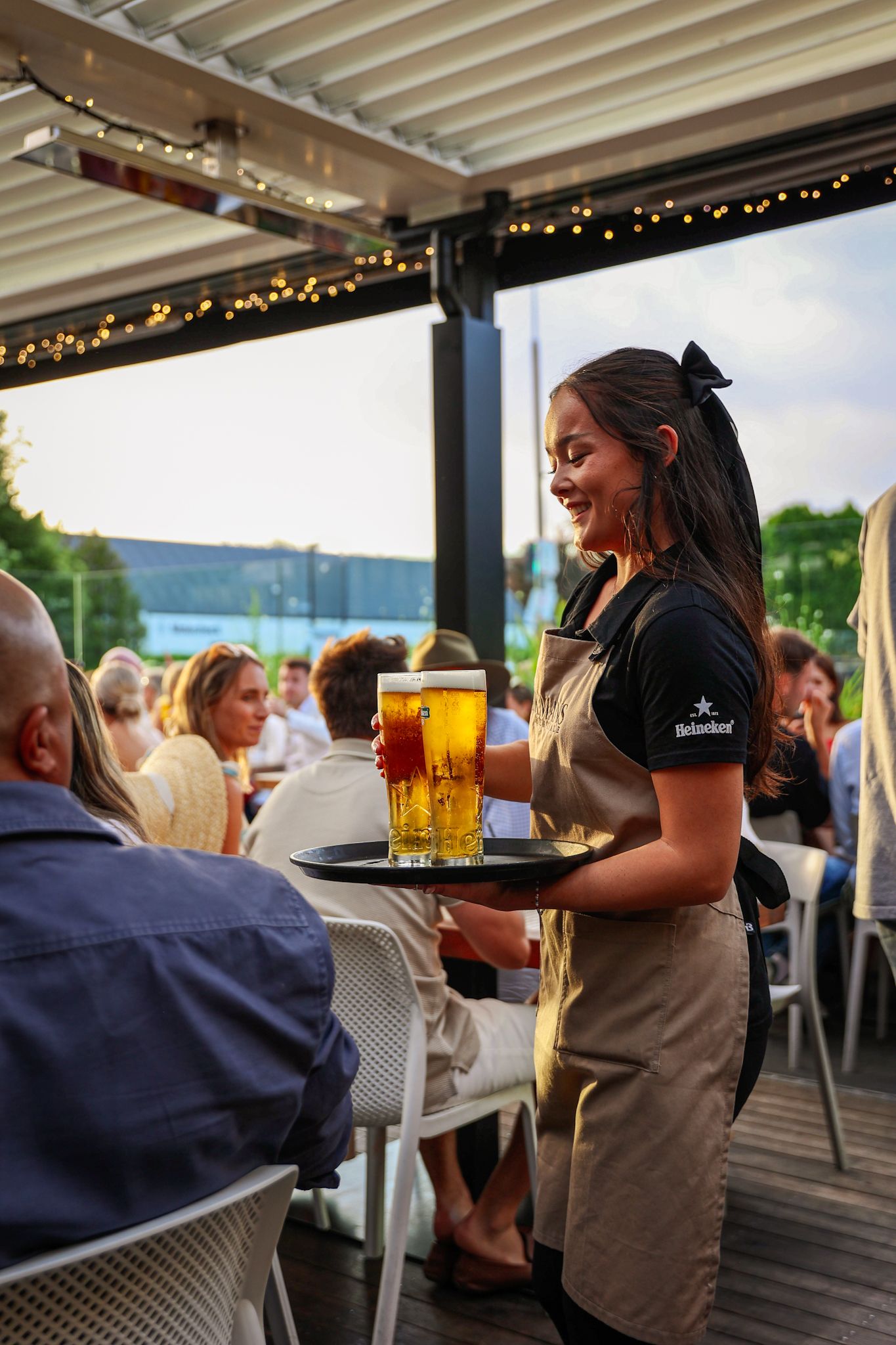 Waitress serving a tray of Heineken pints at Aikmans Merivale