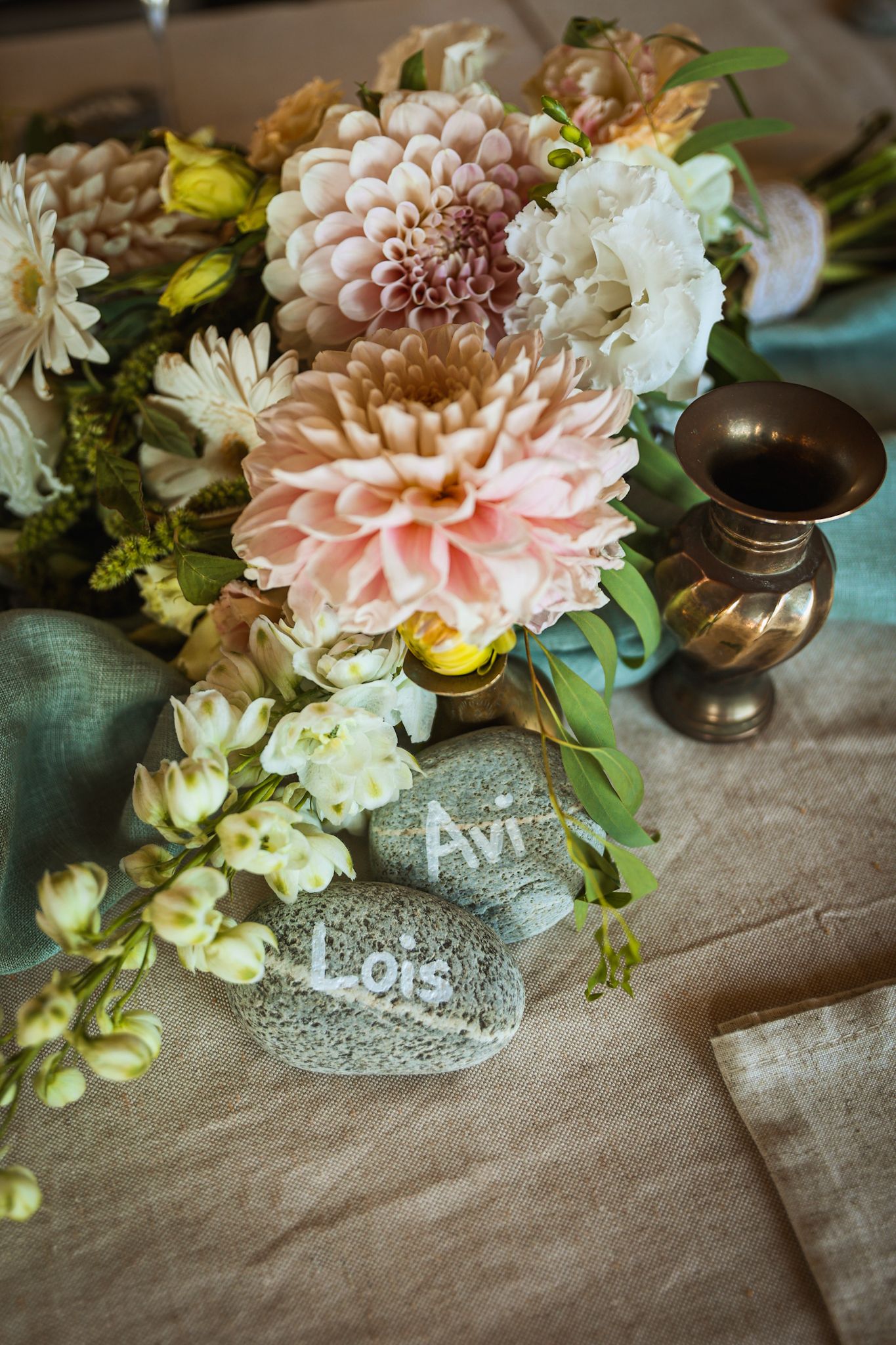 Wedding party table centerpiece. Floral arrangement and stones with names written on
