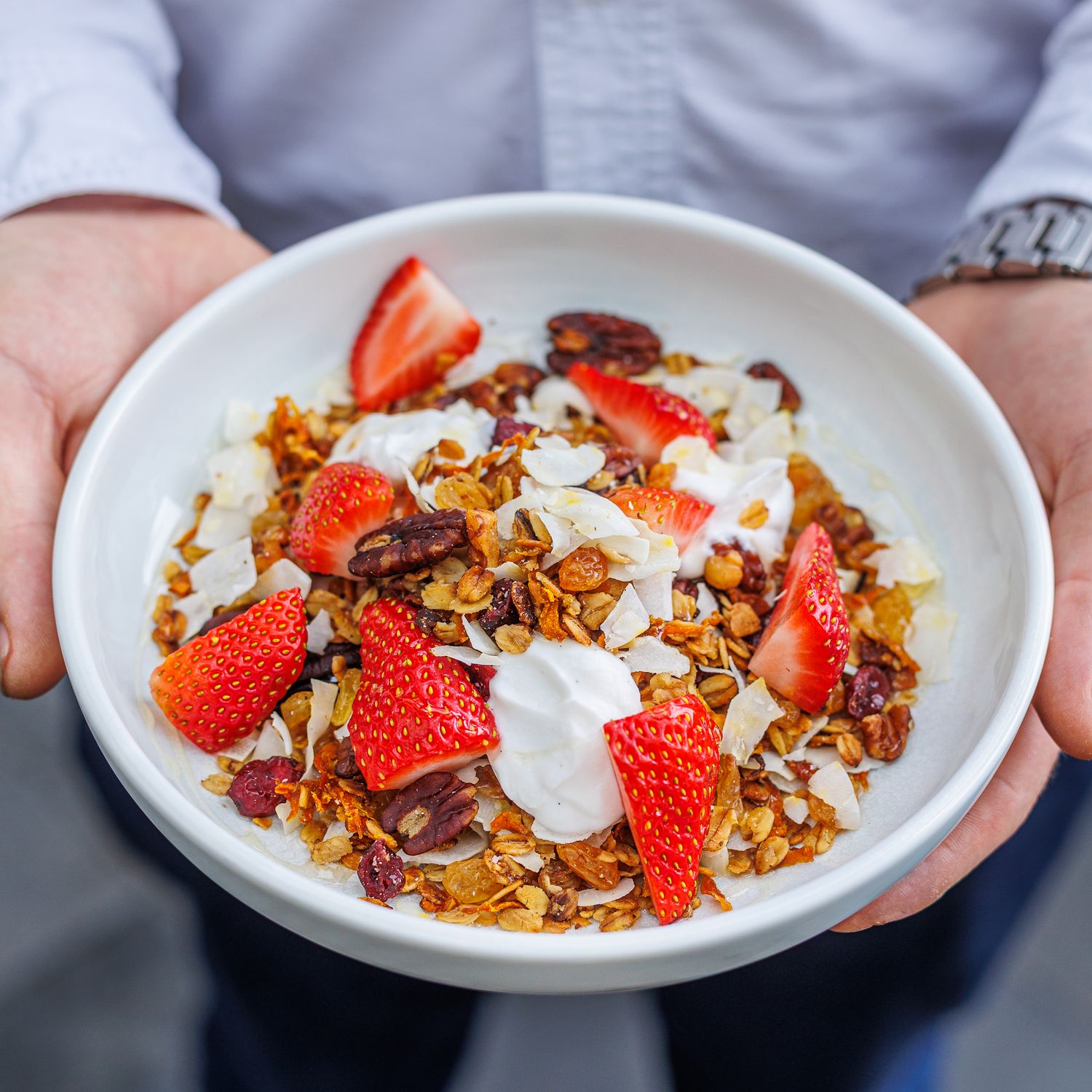 Hands holding a bowl of breakfast berry muesli