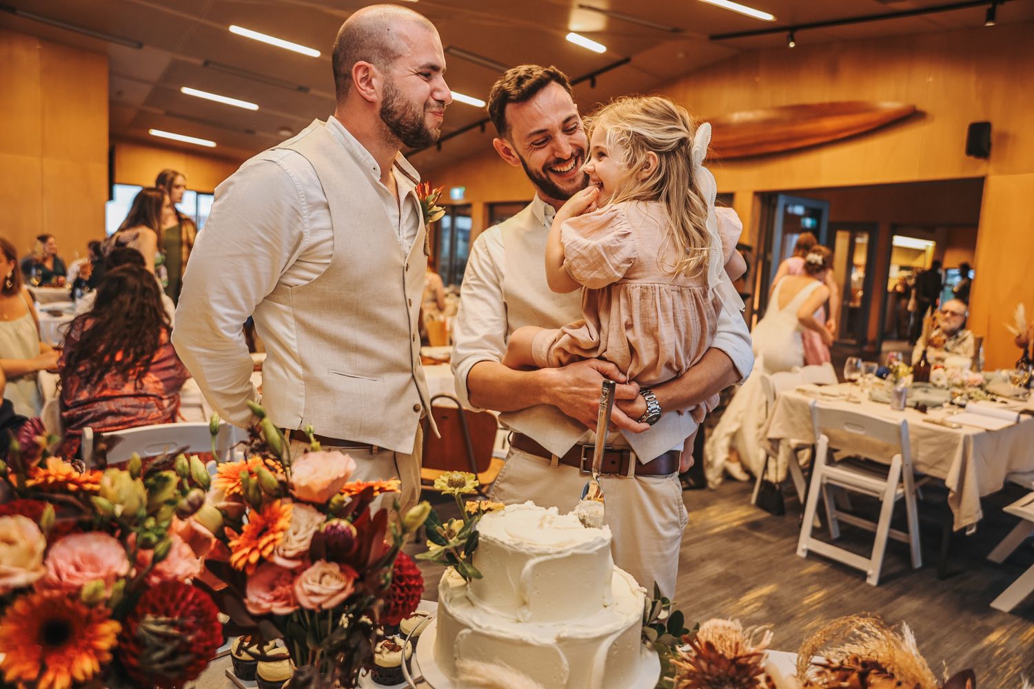 Groom, young daughter and groomsman all enjoying a piece of wedding cake