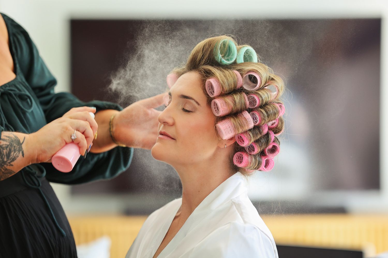 Bride having setting spray applied during her wedding morning makeup session