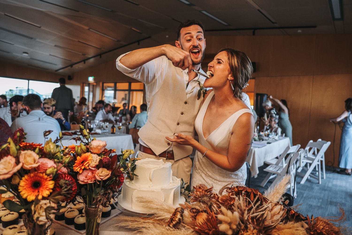 Bride and Groom feeding a slice of cake to each other at their reception.