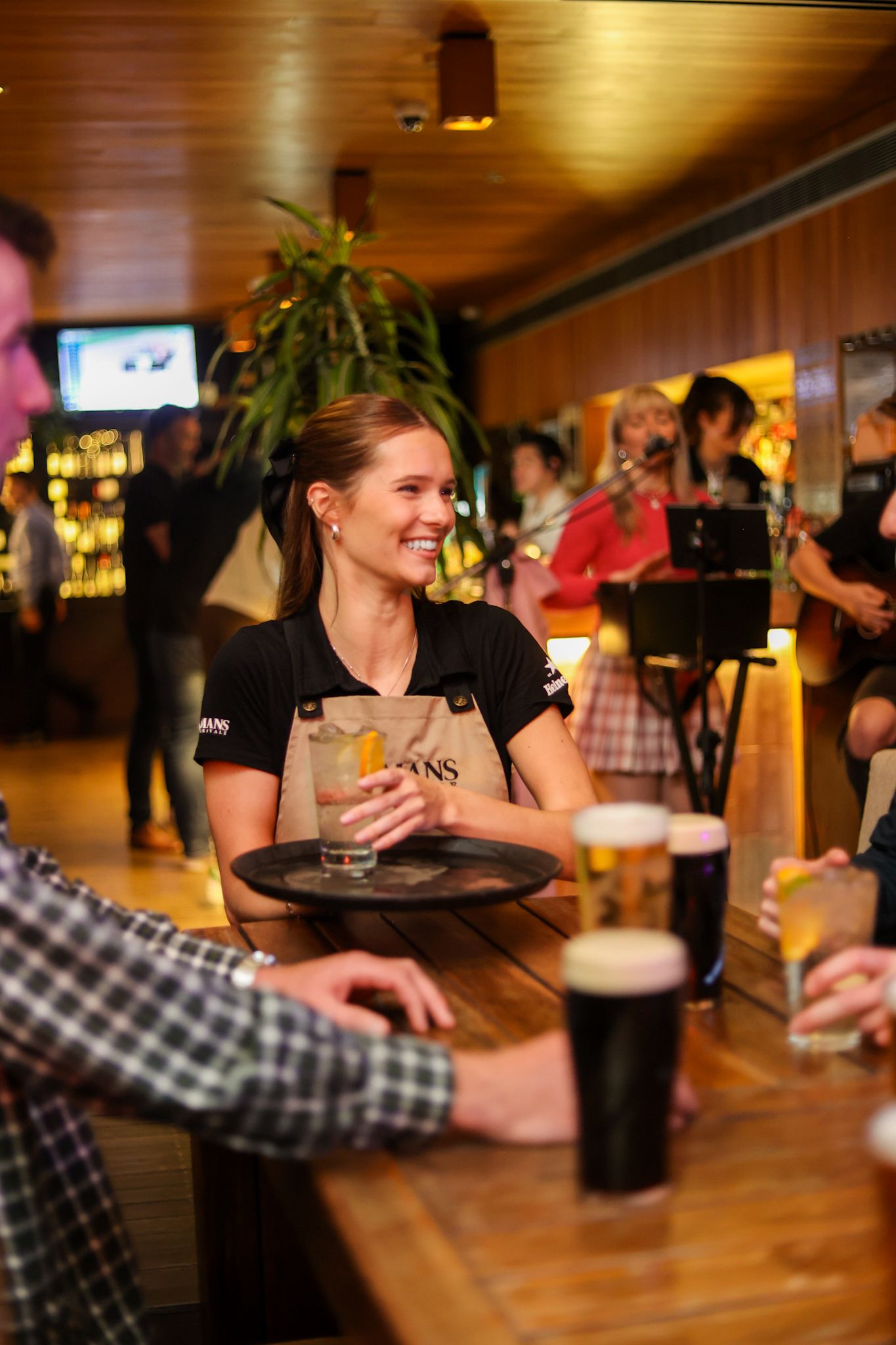 Waitress serving a tray of drinks to a group at Aikmans Merivale