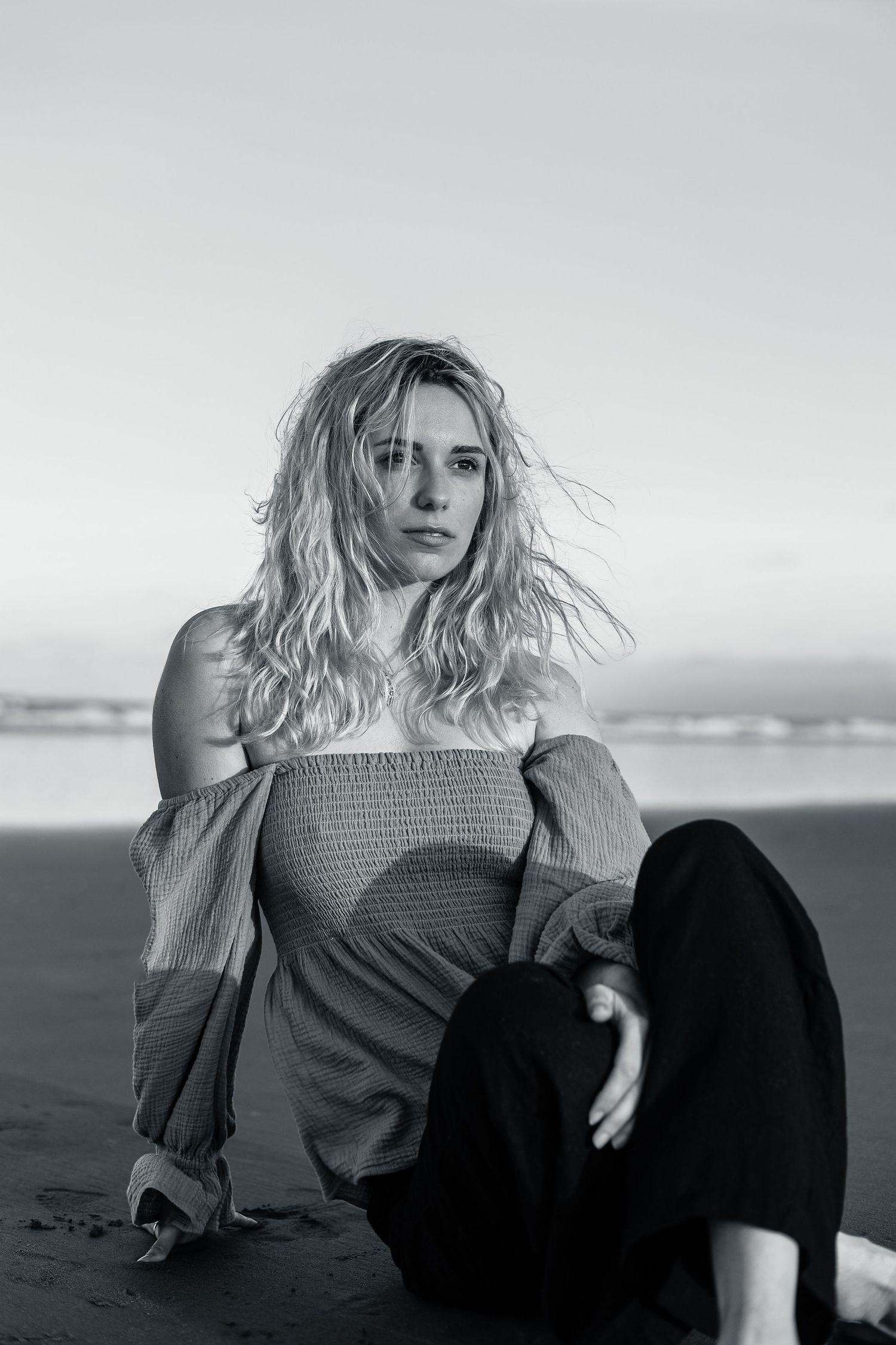 Model sitting on the beach for headshot portfolio photos.