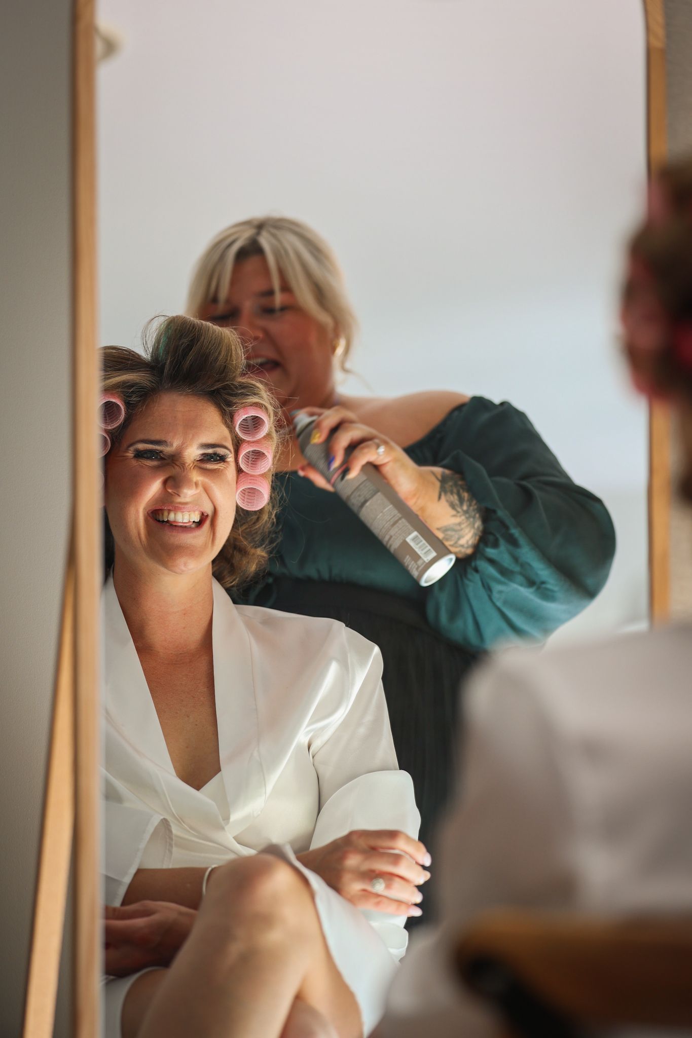 Bride and makeup artist caught through the long mirror, smiling