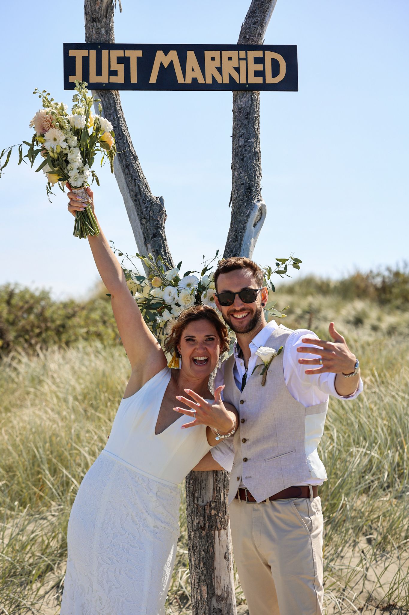 Bride and groom at Southshore New Brighton Beach during their newlywed portraits Standing under a just married sign