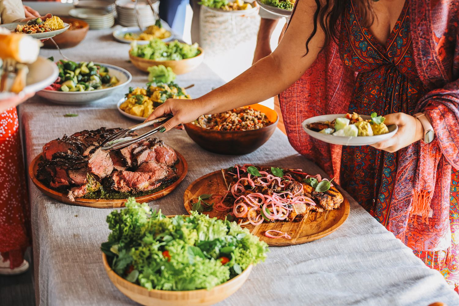 Guests at a wedding plating up salads and steak from a buffet table
