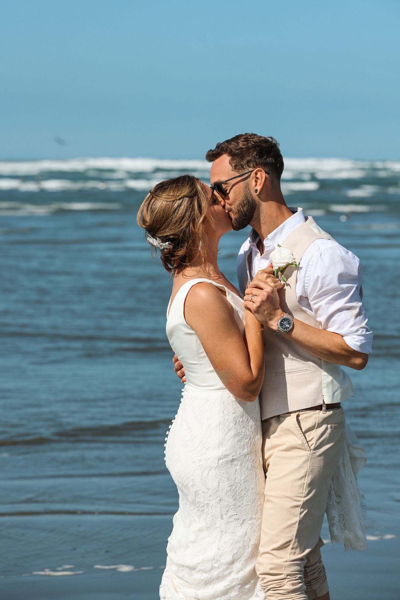 Bride and groom kissing in the surf at Southshore New Brighton Beach during their newlywed portraits