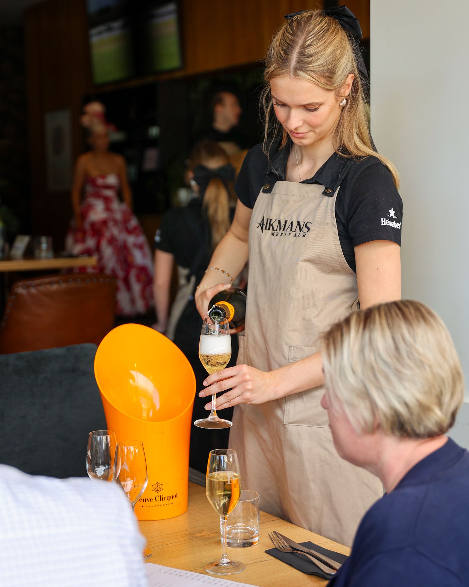 Waitress pouring a glass of Veuve Clicquot Yellow Label Champagne at Aikmans Merivale
