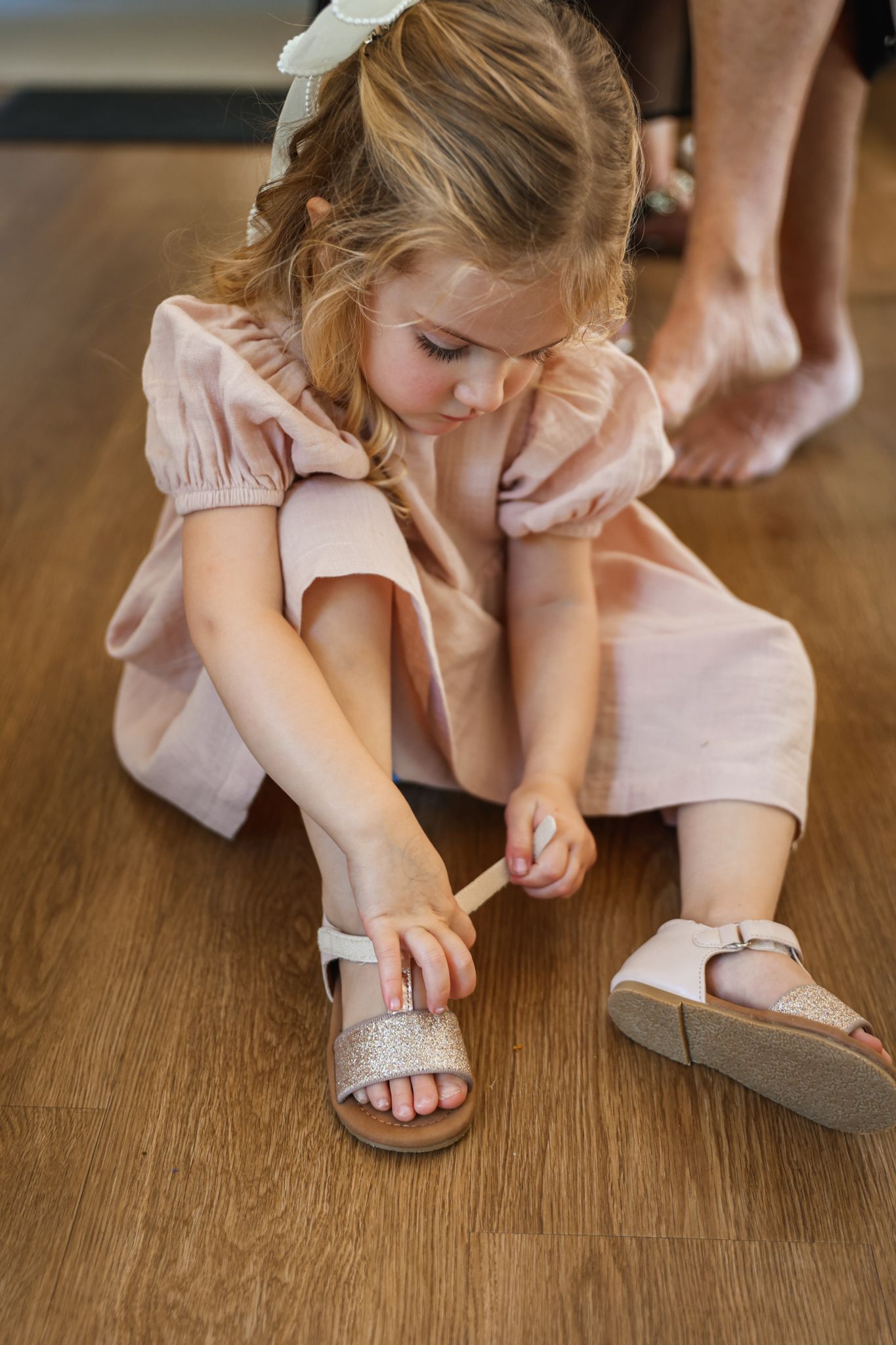 Young girl putting on her sparkly shoes before her mum’s wedding ceremony