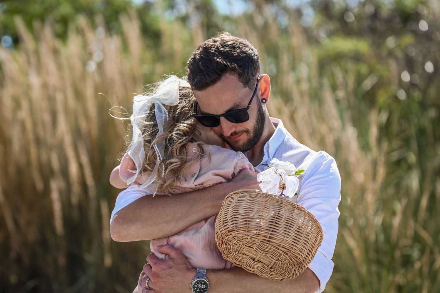 Groom and young daughter hugging in a natural candid moment.
