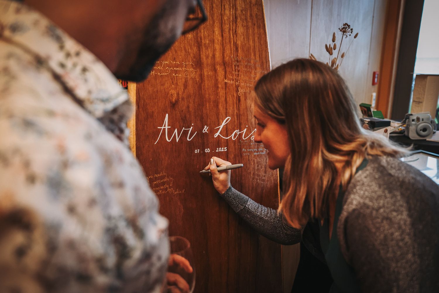 Guests handwriting their well-wishes onto a surfboard at a wedding reception