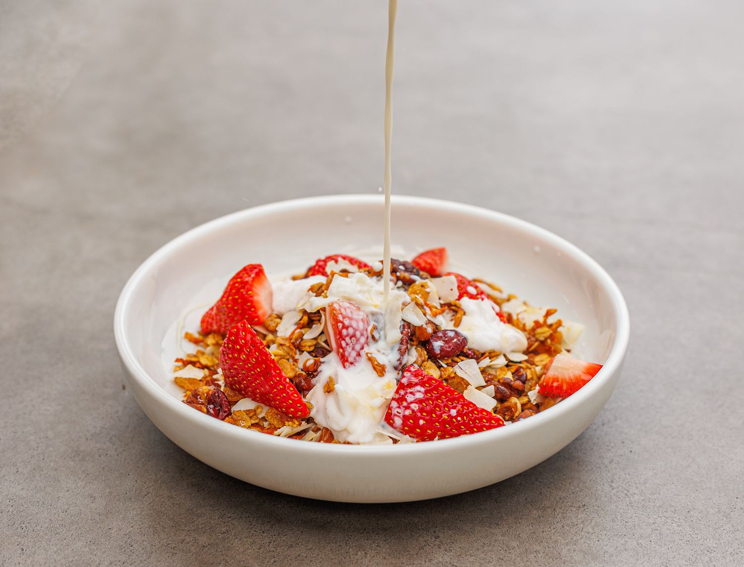 Milk poured over a bowl of breakfast muesli