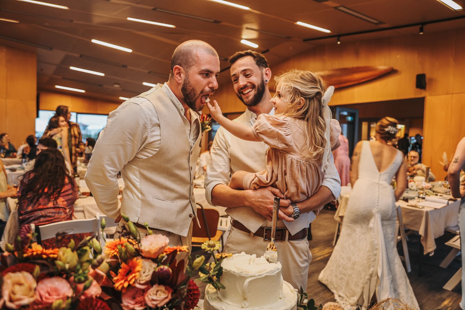 Groom, young daughter and groomsman eating wedding cake