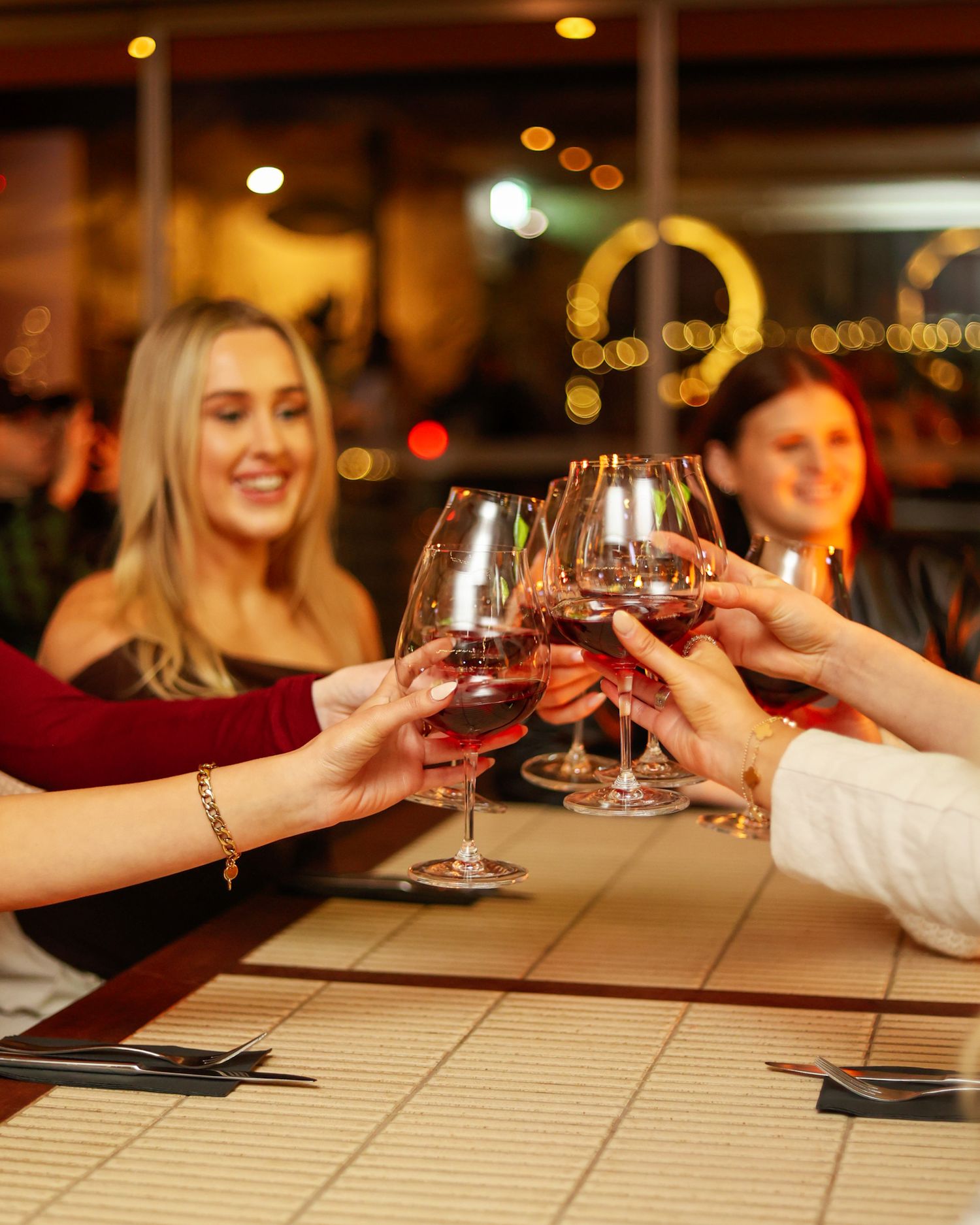Group of ladies toasting with red wine glasses at a restaurant.